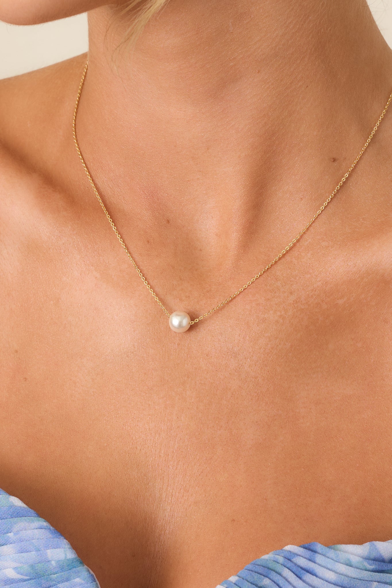 Close-up of the Simply The One Pearl Gold Solitaire Necklace featuring a single round pearl suspended on a delicate gold chain.