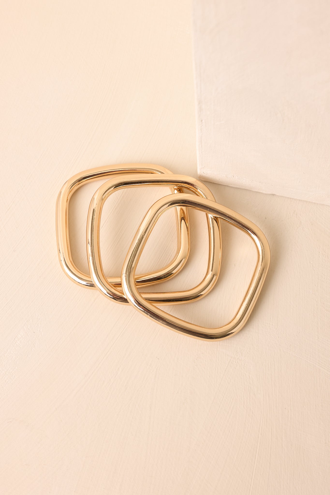 A detailed shot of the square-shaped gold bangles showing smooth edges and a glossy metallic surface.
