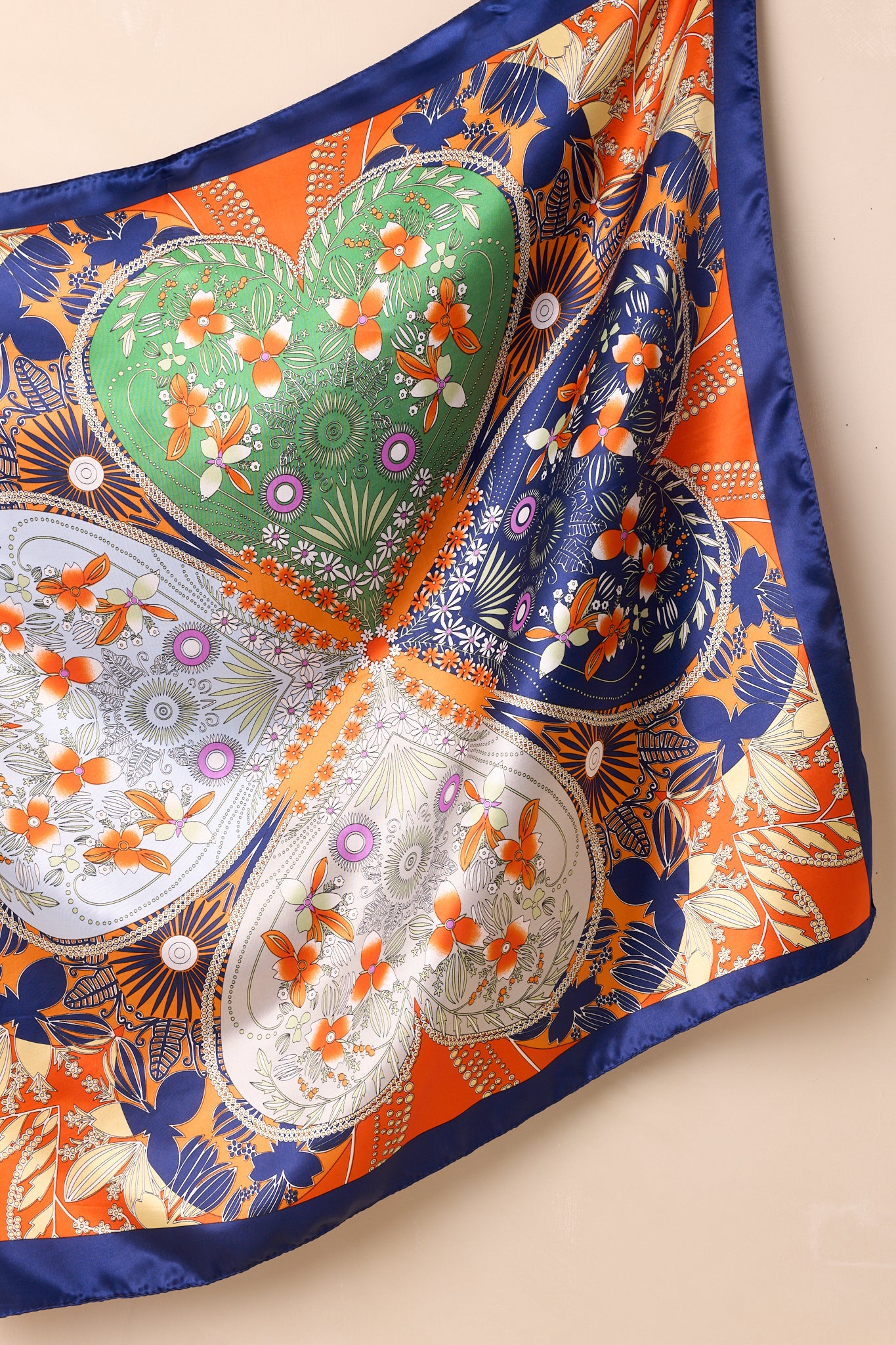 Square orange scarf with multicolor floral geometric print and four-leaf lover motif, featuring a satin finish and contrast border.
