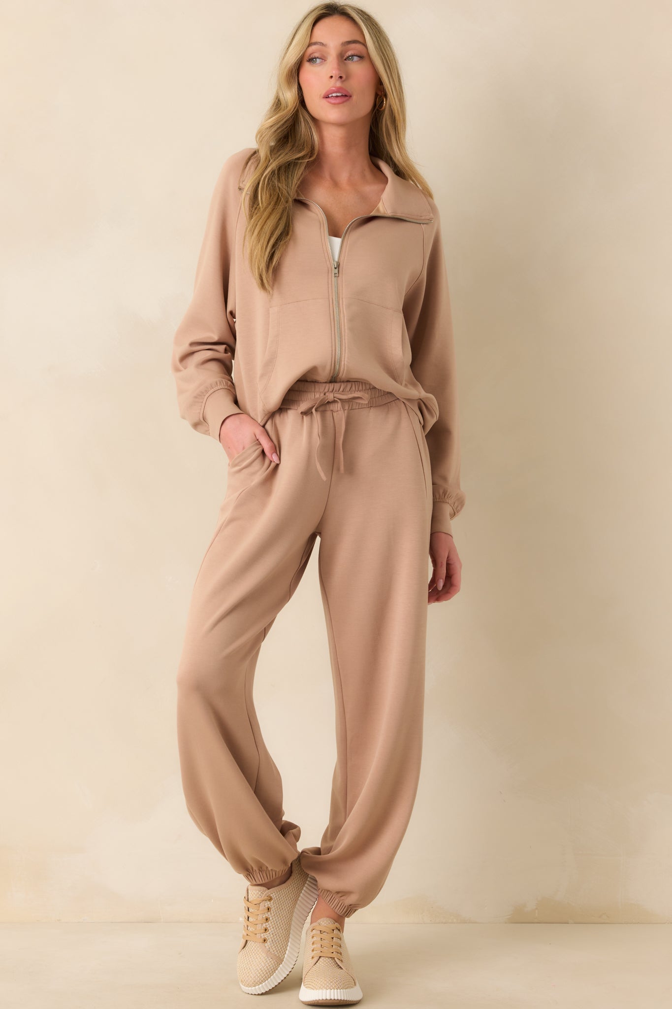 A full body front view of the tan jacket showing the zip front closure, collared neckline, and structured shape.