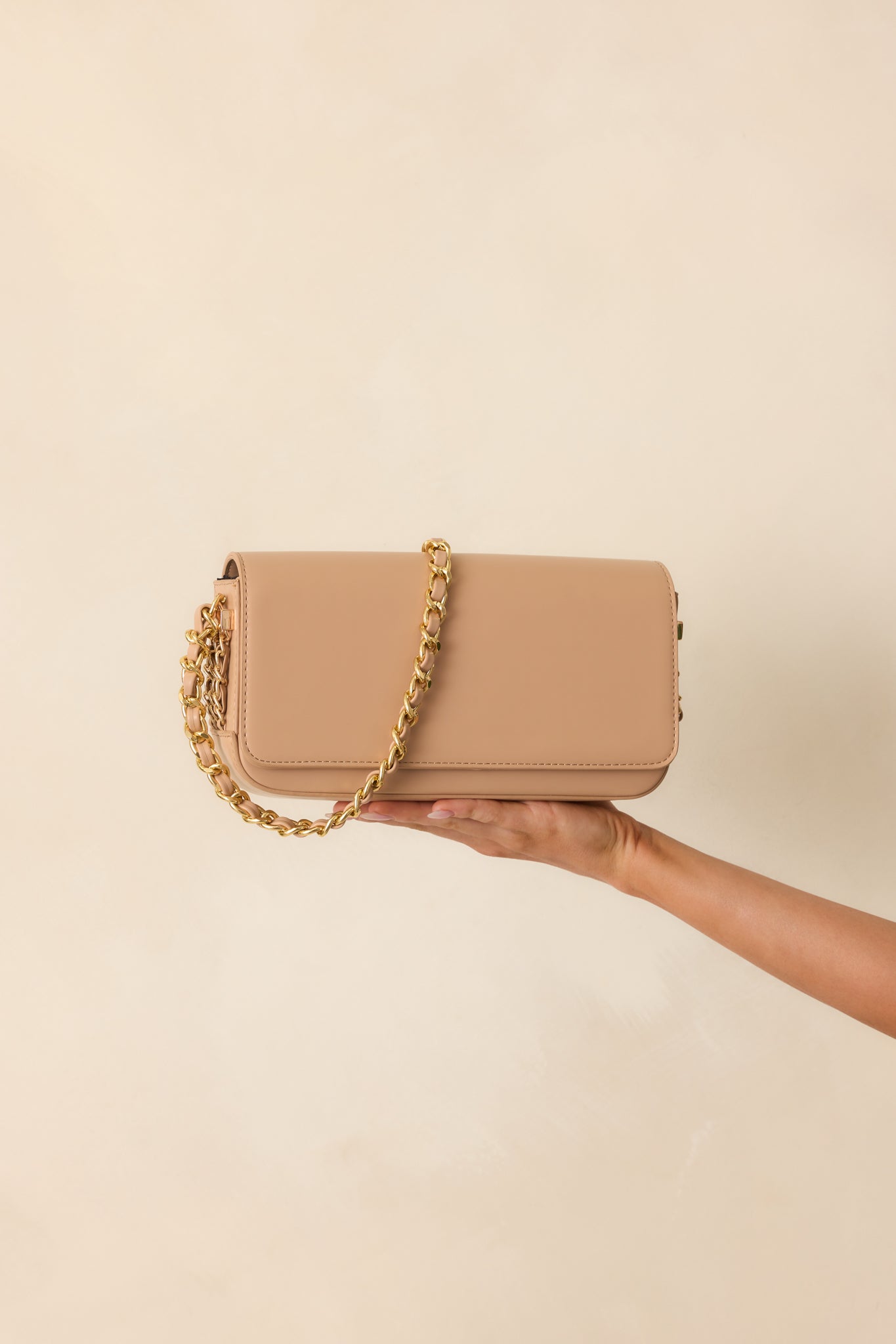 Cropped view focusing on the magnetic flap closure and smooth beige faux leather material of the handbag.