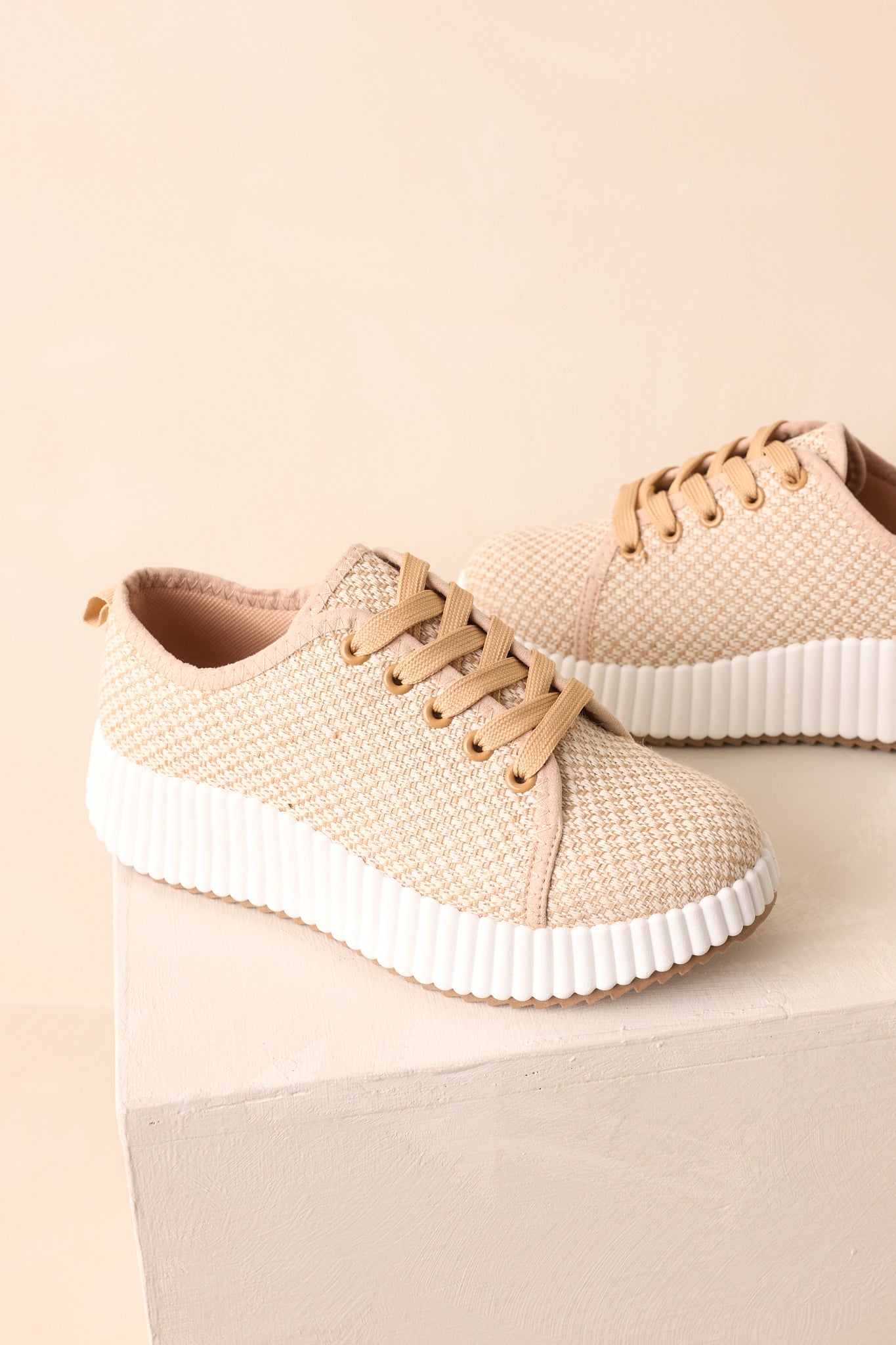 Platform sole and woven texture detail highlighted on tan sneakers.