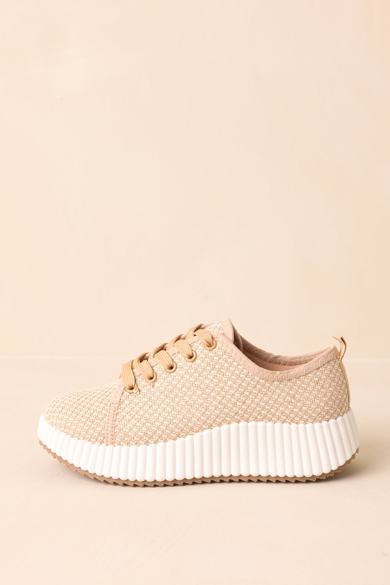 Side view of tan sneakers highlighting woven fabric and cushioned platform sole.
