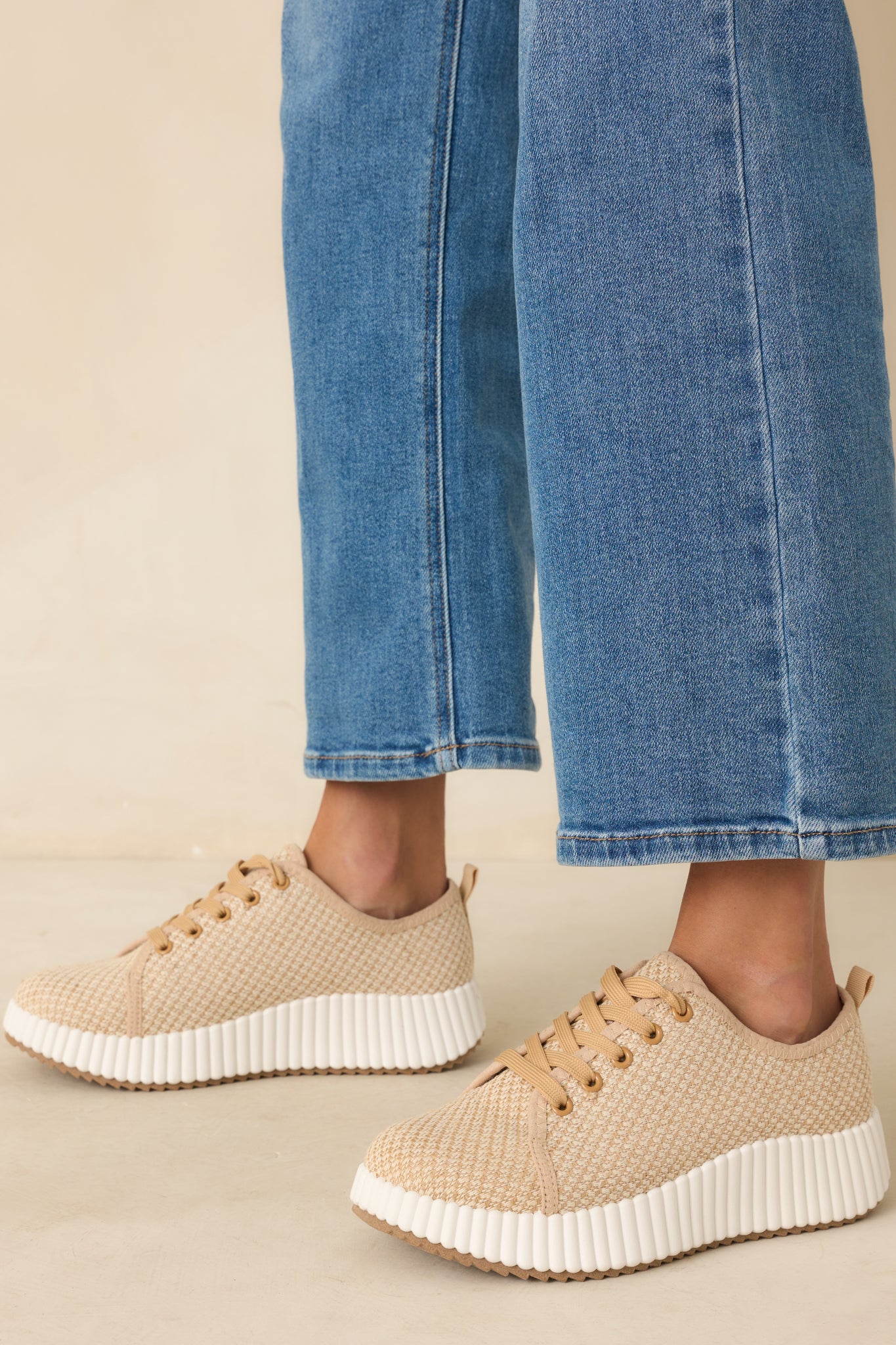 A side angle view of the tan sneakers showing the woven fabric upper and white rubber platform sole.