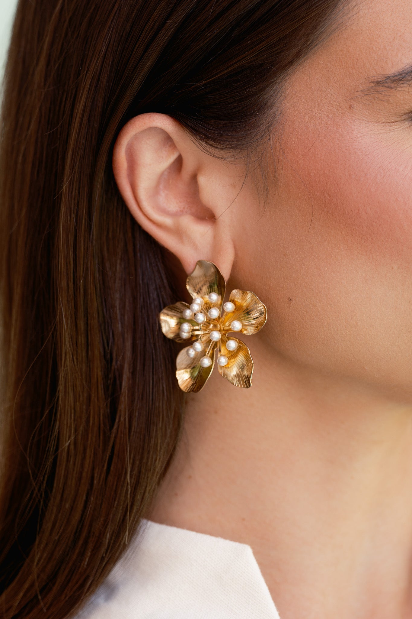 A cropped image highlighting the dimensional pearl cluster surrounded by textured gold petals.