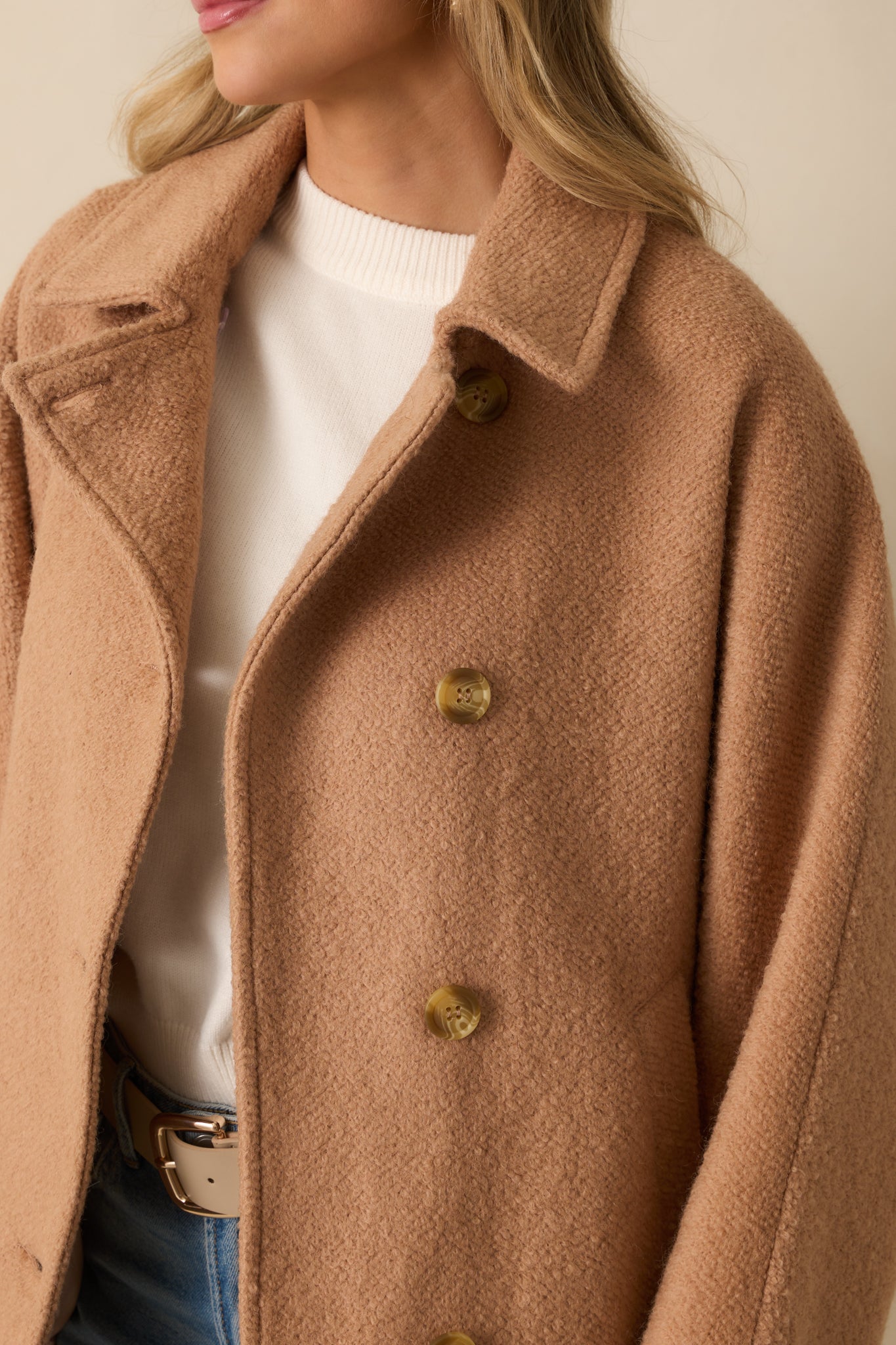 Textured wool-blend fabric of the camel coat highlighted in detail.