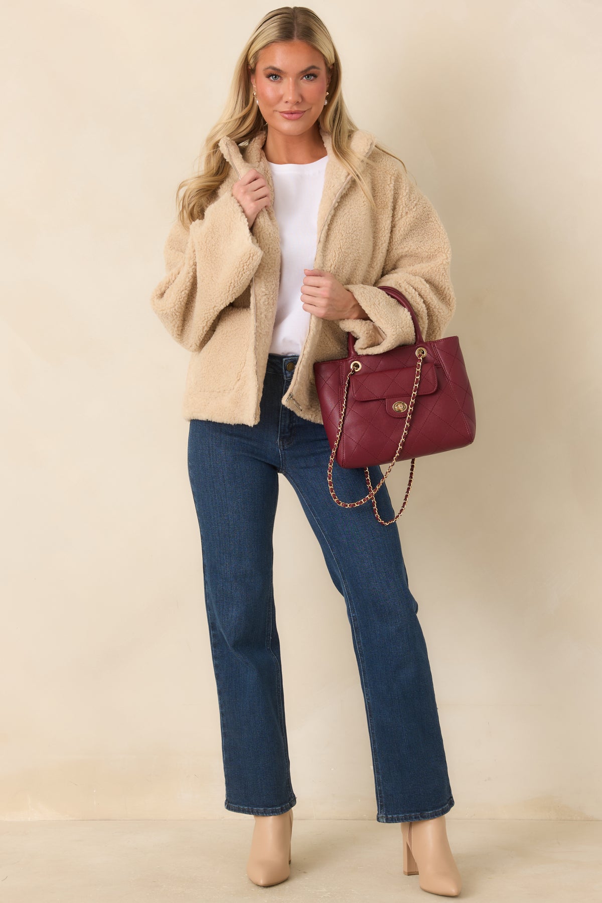 Model wearing The Daily Edit dark wash straight leg jeans with ankle-length hems, styled with beige heeled boots.