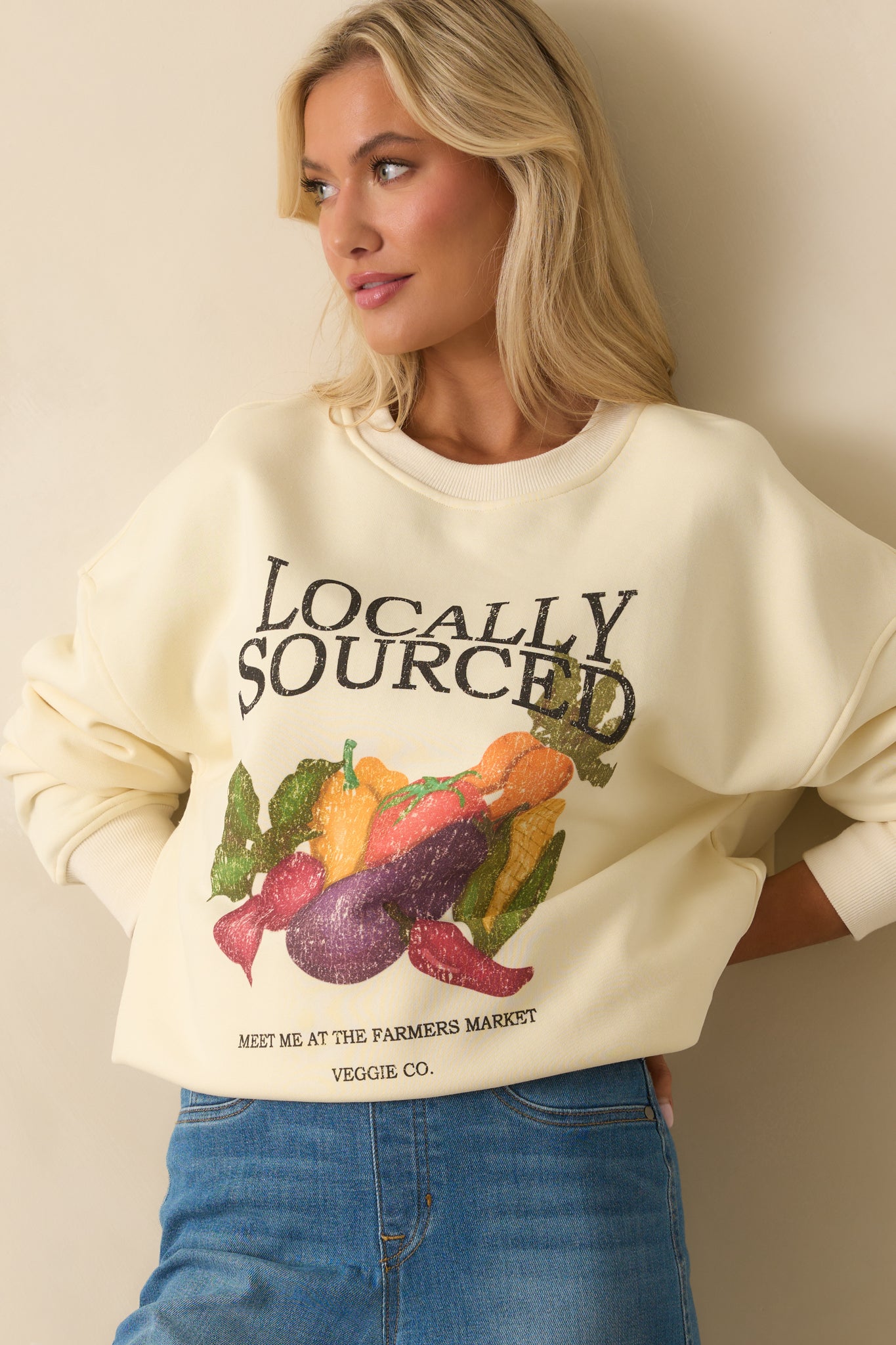 Torso view of ivory sweatshirt with crew neckline and 'Locally Sourced' text graphic.