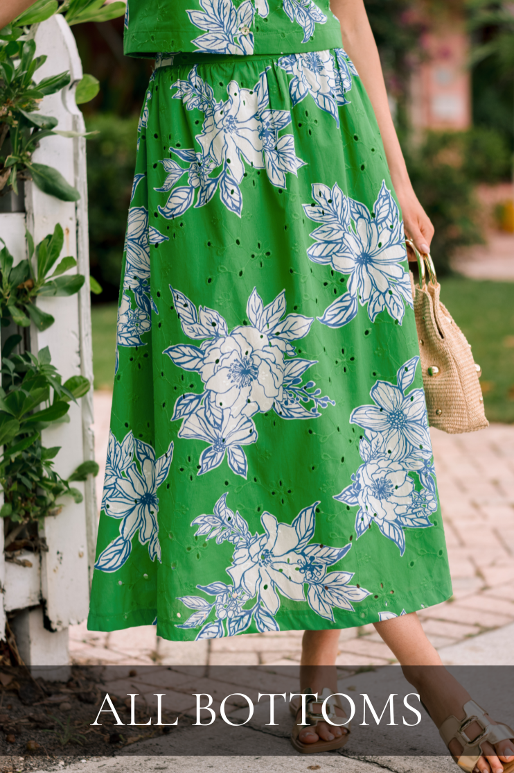 Model standing outside wearing a green and white floral eyelet midi skirt with a lightweight flowing silhouette, elastic waistband, and soft floral print for a fresh spring look. Skirt is featured in All Bottoms shop.