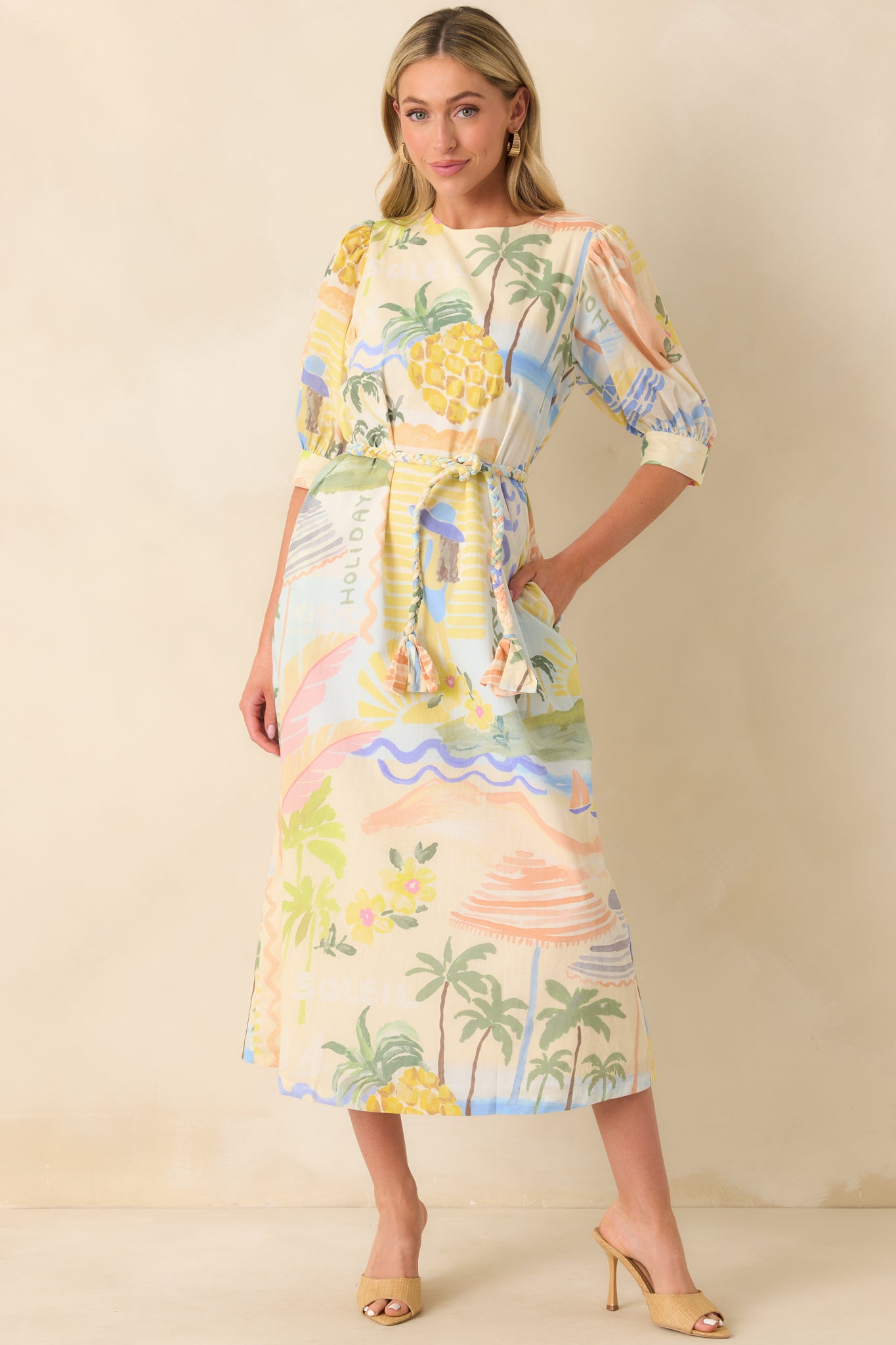 Full body of Prosperina tropical print midi featuring a round neckline, half sleeves, functional button cuffs, and optional braided self-tie belt.