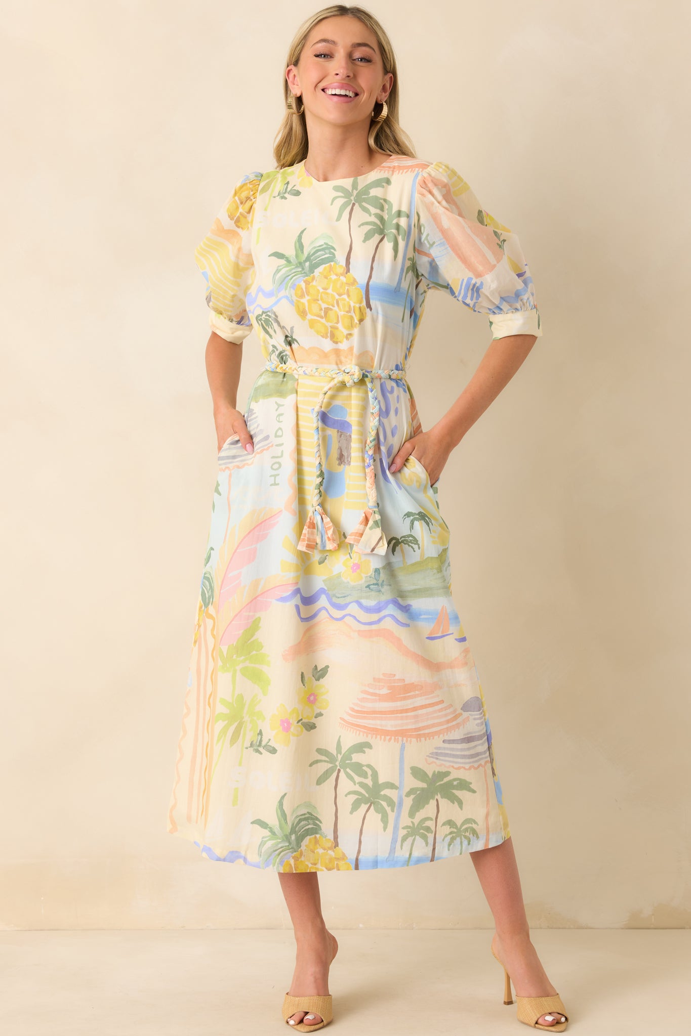 Full body of Prosperina tropical print midi featuring a round neckline, half sleeves, functional button cuffs, functional pockets, and optional braided self-tie belt.