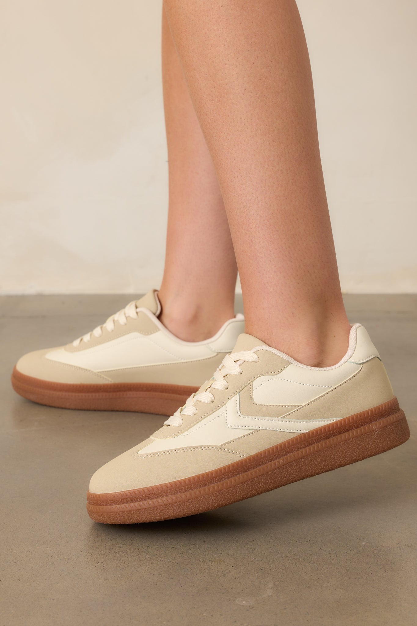 A side-angle shot of the sneakers, showcasing the white accent pieces on the side, beige panels, and the contrast of the thick brown sole.