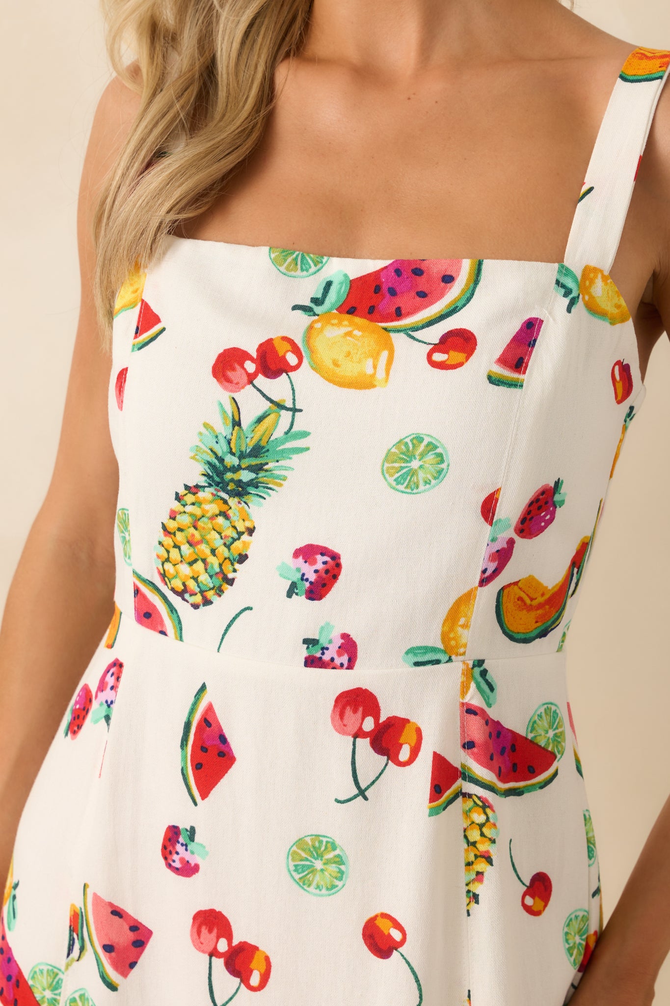 Close-up of the fruit print and fabric texture, showing the fine multicolor detailing on the ivory background and the edge of the square neckline.
