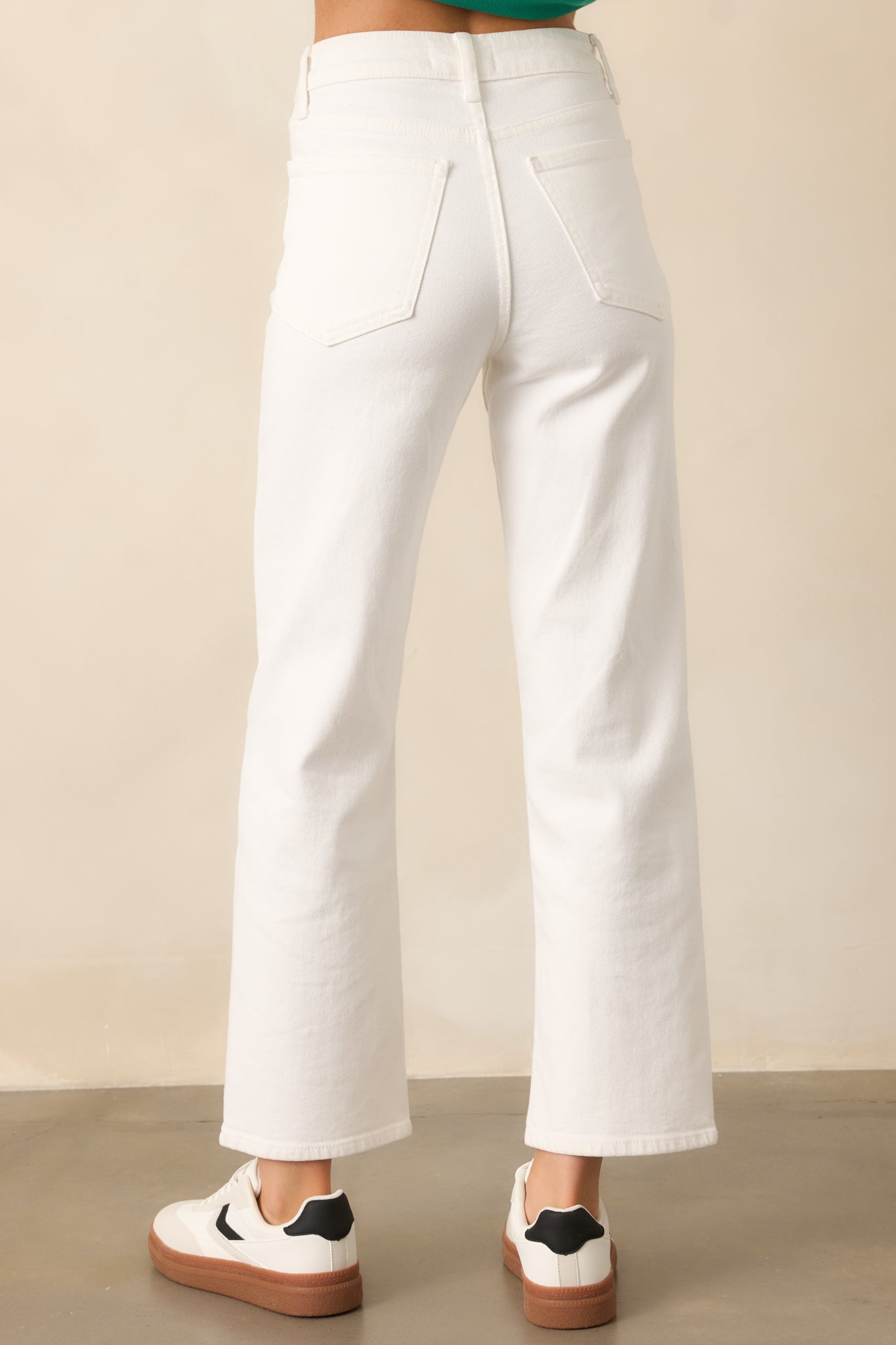 The back view of these white jeans highlights their clean, classic design with functional pockets and a flattering high-waisted fit.