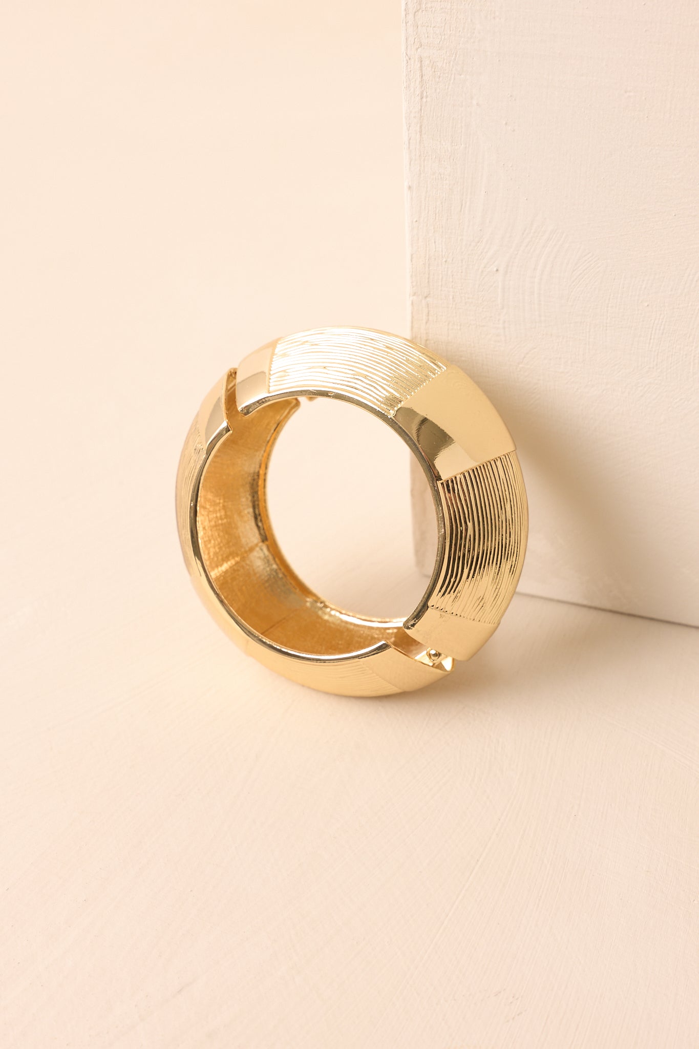 A cropped view of the wide gold cuff bracelet with alternating polished and engraved textured panels.