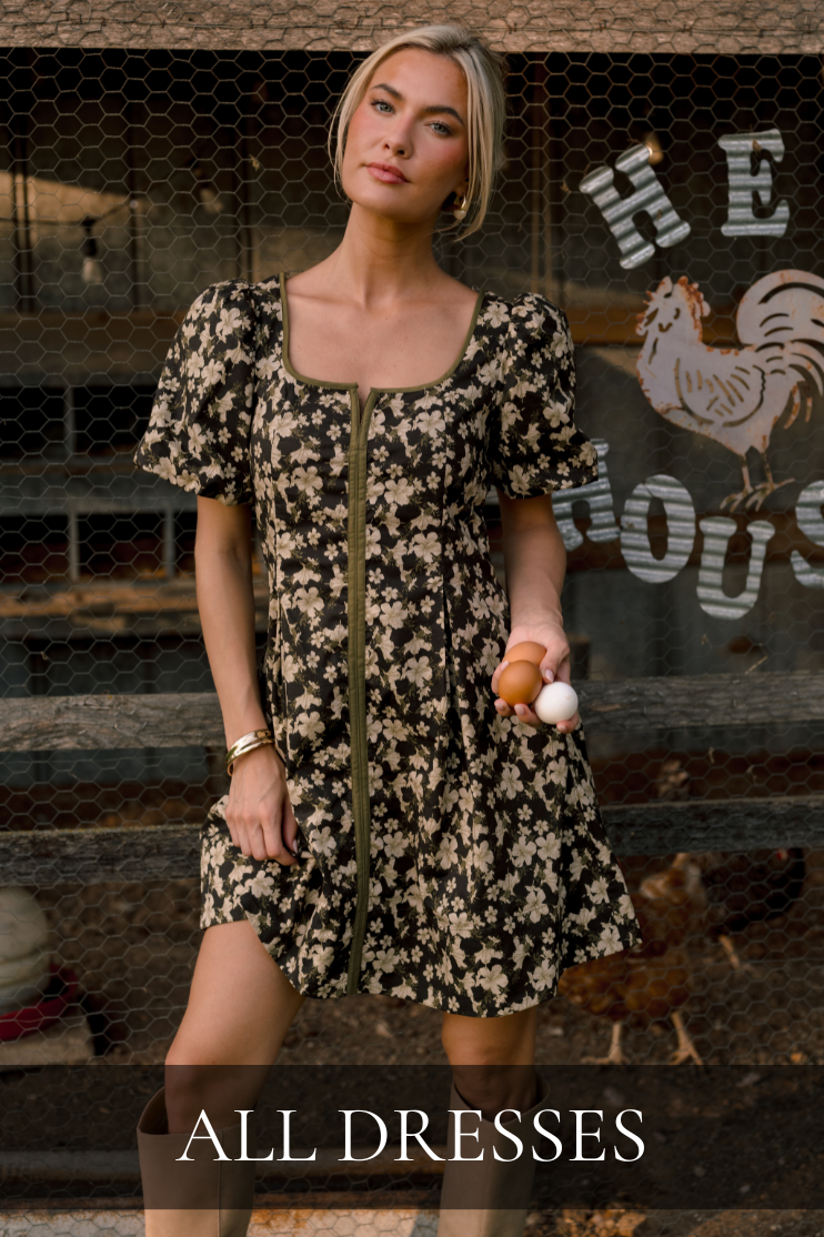 Woman wearing a black floral puff sleeve mini dress, featured in the All Dresses shop.