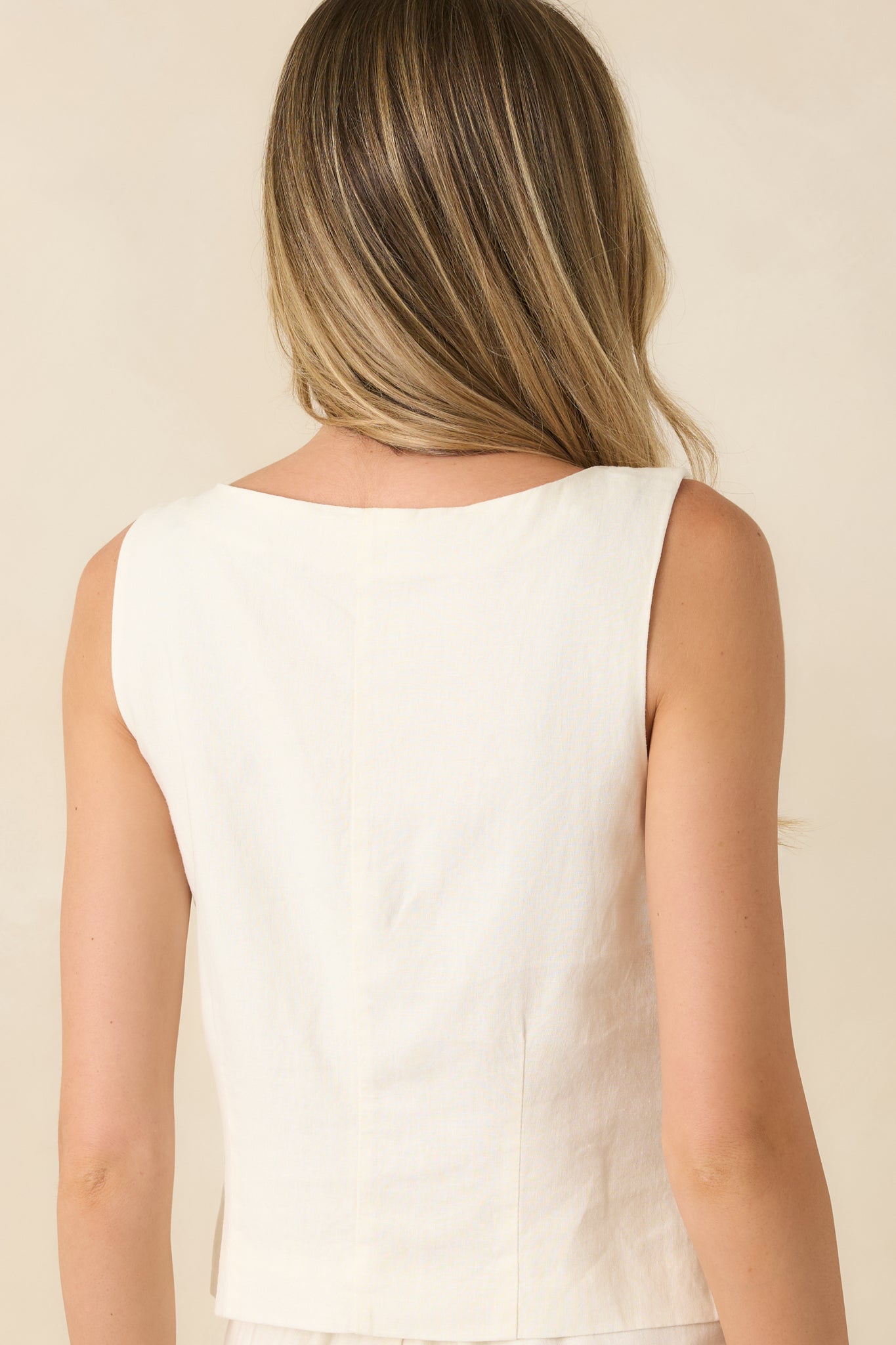Back view of the ivory vest highlighting the sleeveless silhouette, structured seams, and clean tailored shape.