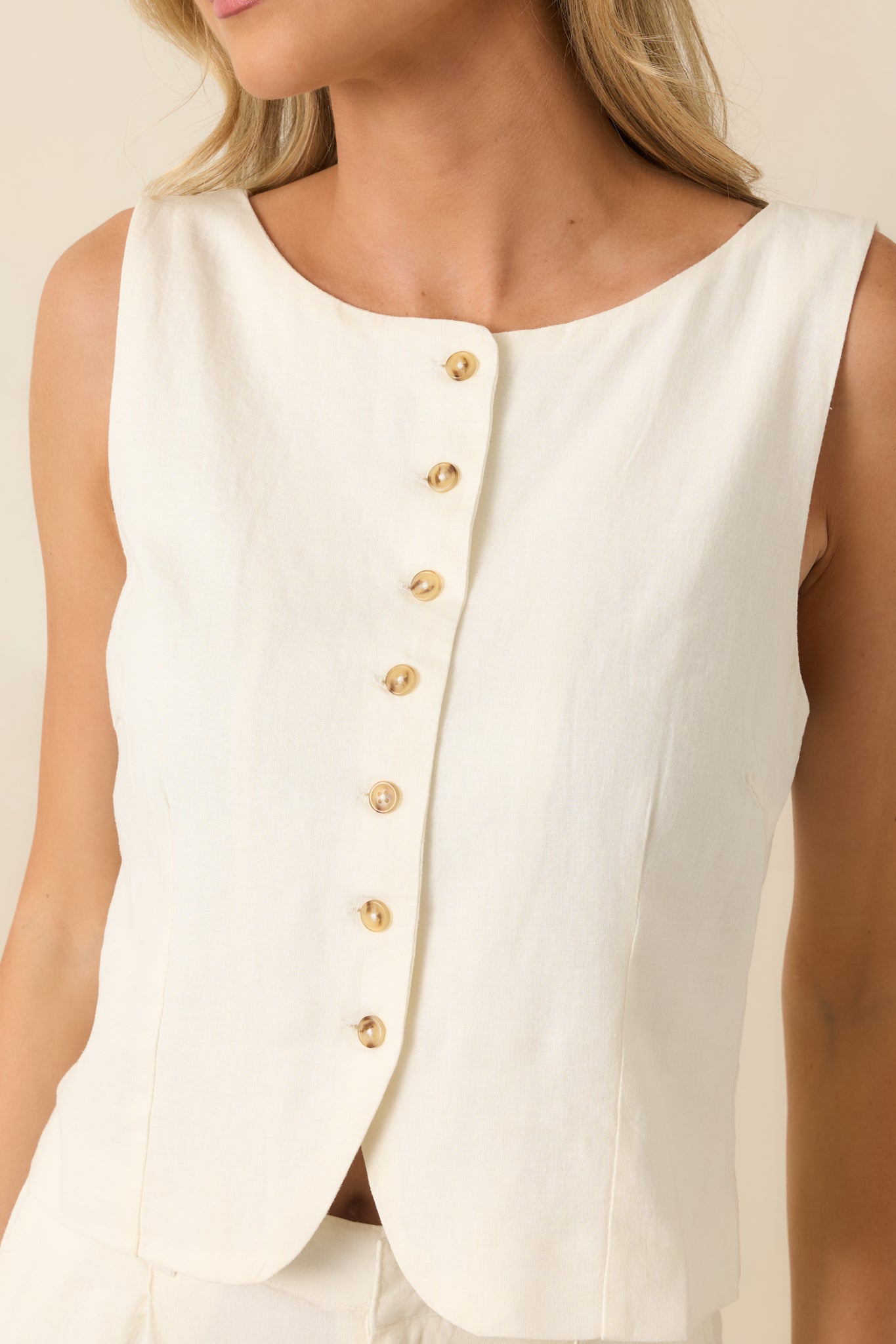 Close-up of the ivory vest featuring the tortoise-inspired buttons, linen blend texture, and precise tailored stitching.