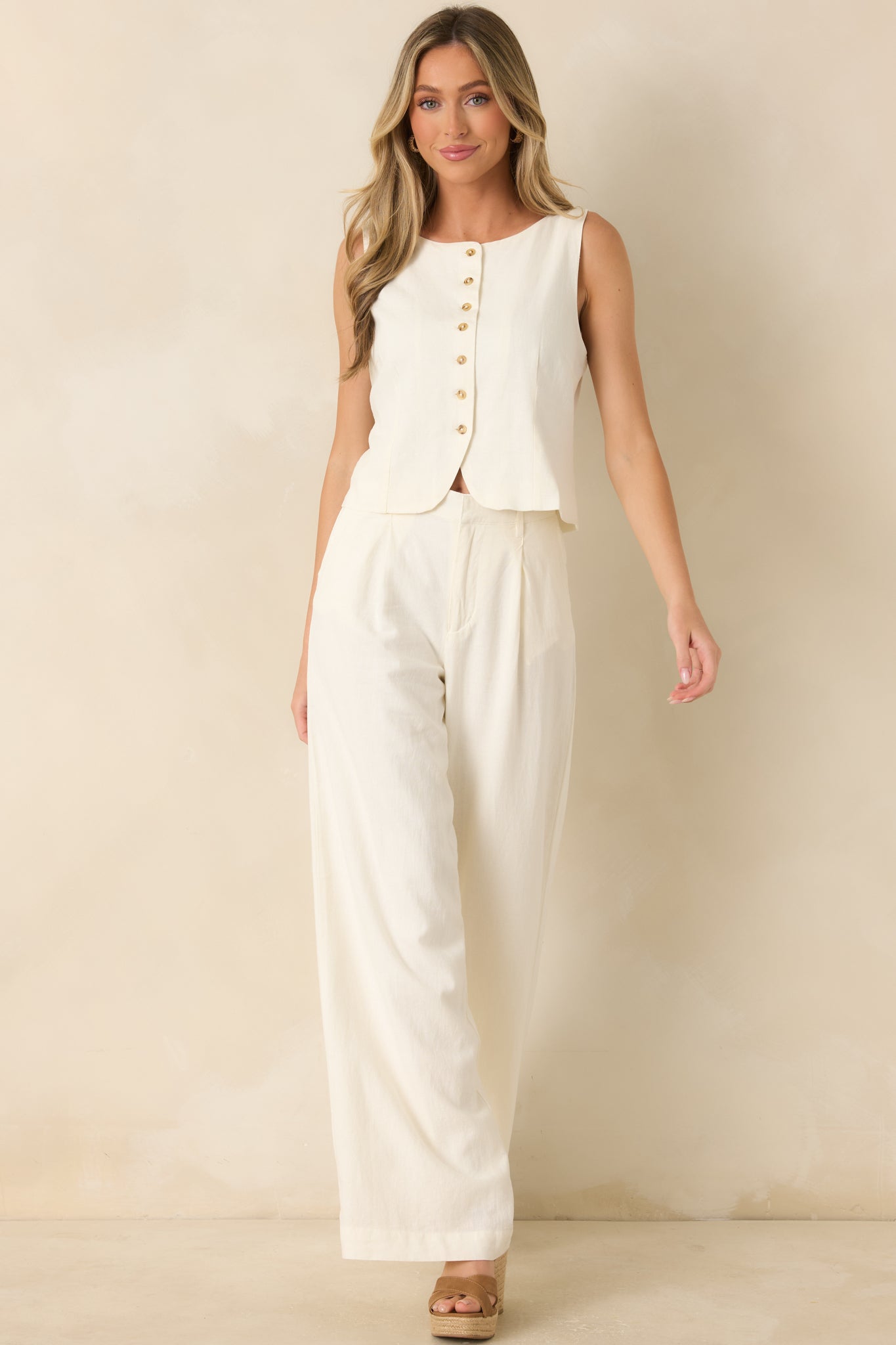 Ivory linen blend vest featuring a sleeveless design, rounded neckline, tortoise-inspired buttons, and tailored seam detailing.