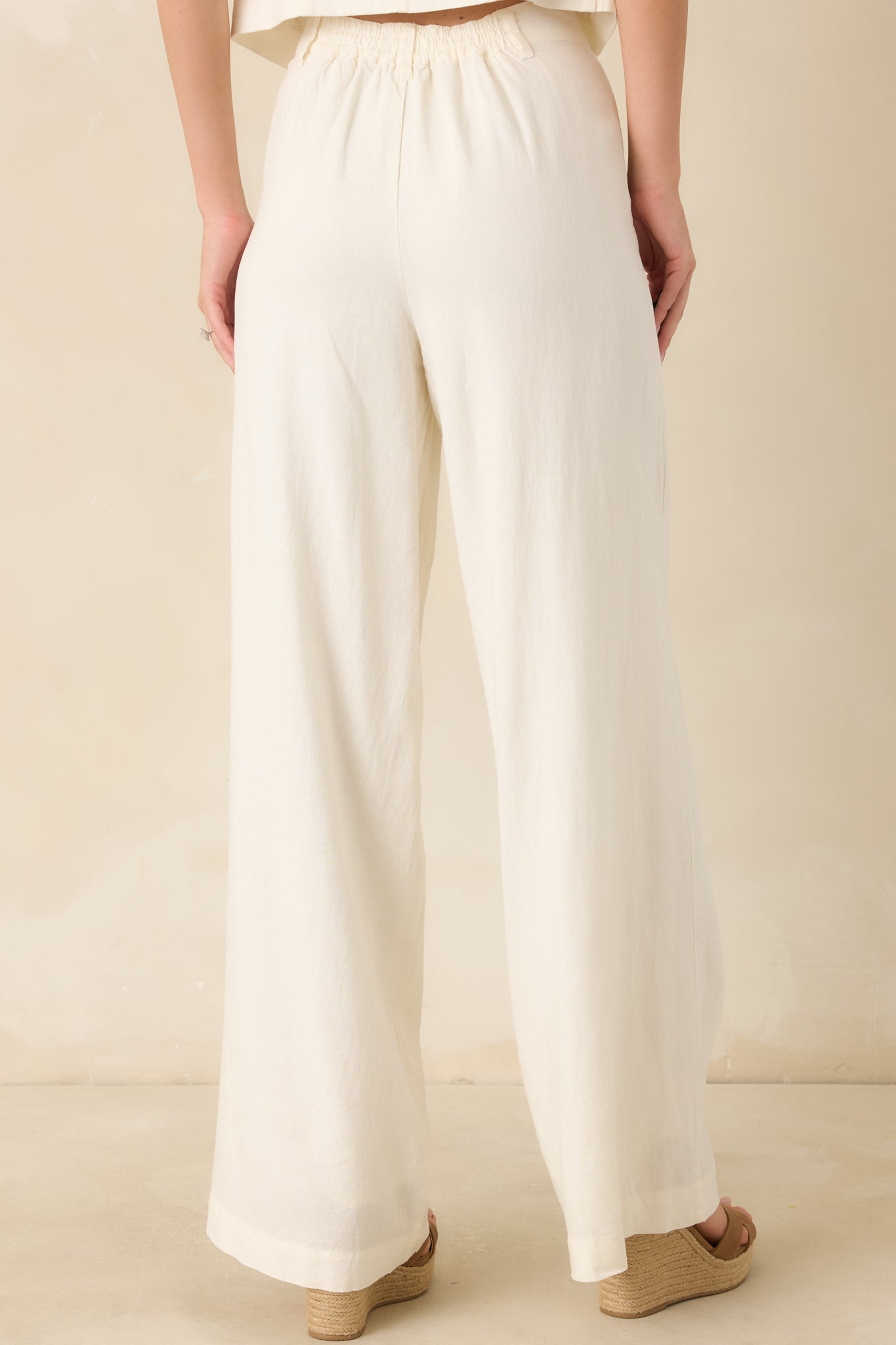 Back view of the ivory linen blend pants highlighting the elastic waistband, straight-leg fit, and fully lined construction.