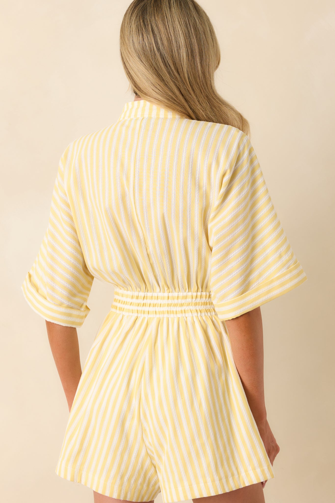 Back view of yellow striped romper showcasing elastic waistband and relaxed fit for a flattering look.
