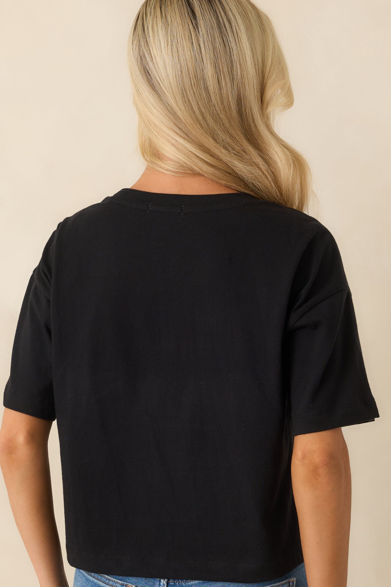 Rear view of the black tee highlighting the short sleeves, straight hem, and relaxed fit from the back.