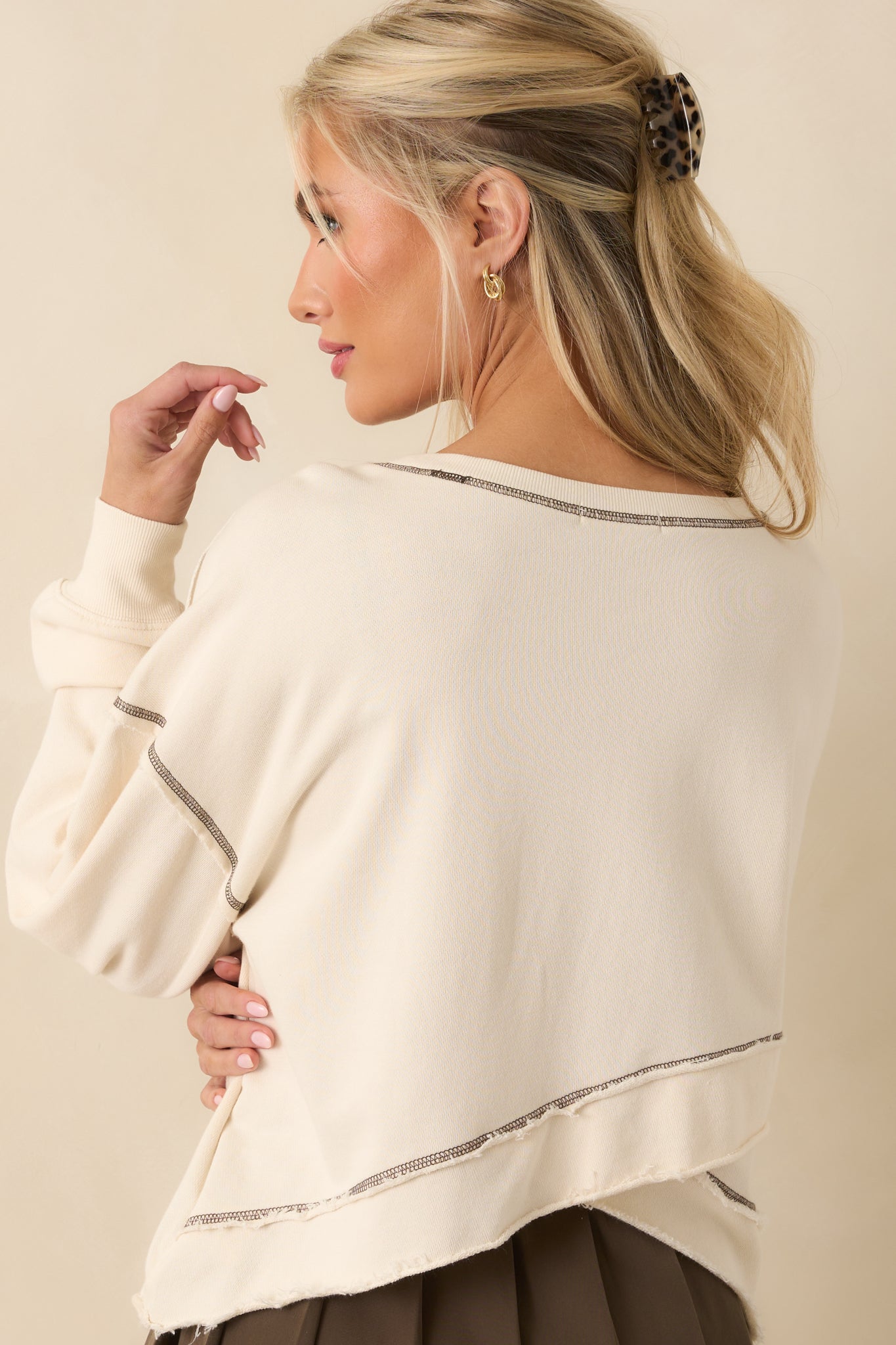 Rear view of the ivory sweatshirt featuring a surplice back design and long sleeves with brown topstitch accents.