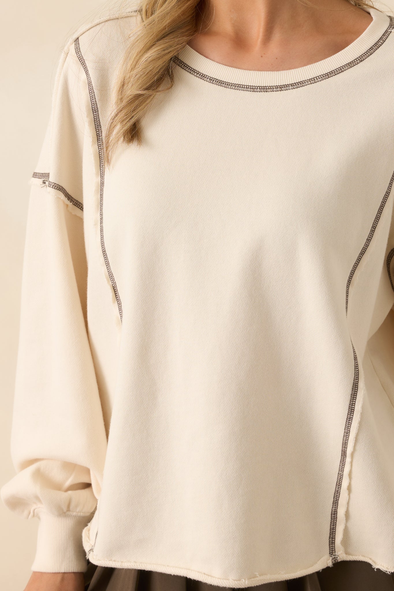 Detailed close-up of the ivory sweatshirt fabric, showing brown topstitching and the soft, moisture-wicking terry material.
