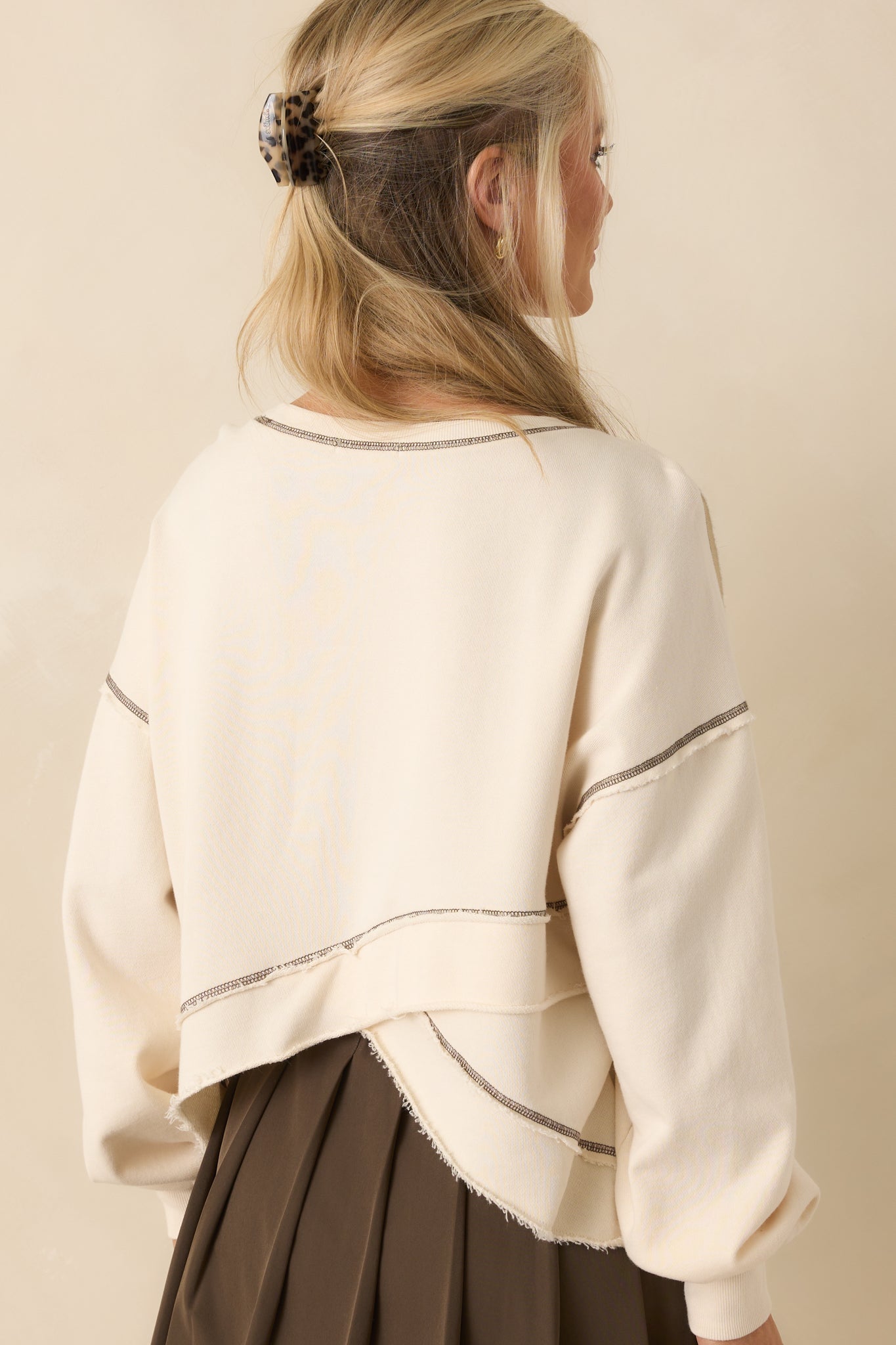 Ivory sweatshirt shown from the back, highlighting the overlapping surplice design, long sleeves, and subtle brown topstitch details along the seams.