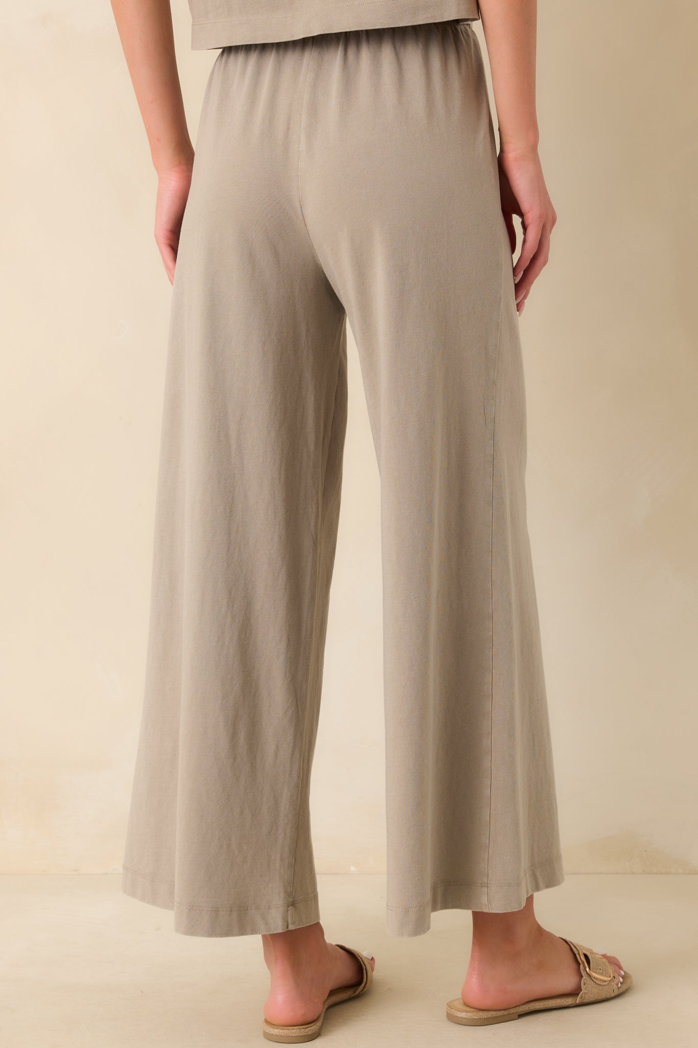 A back view of the taupe pants featuring the high waist and relaxed fit continuing through the wide legs.