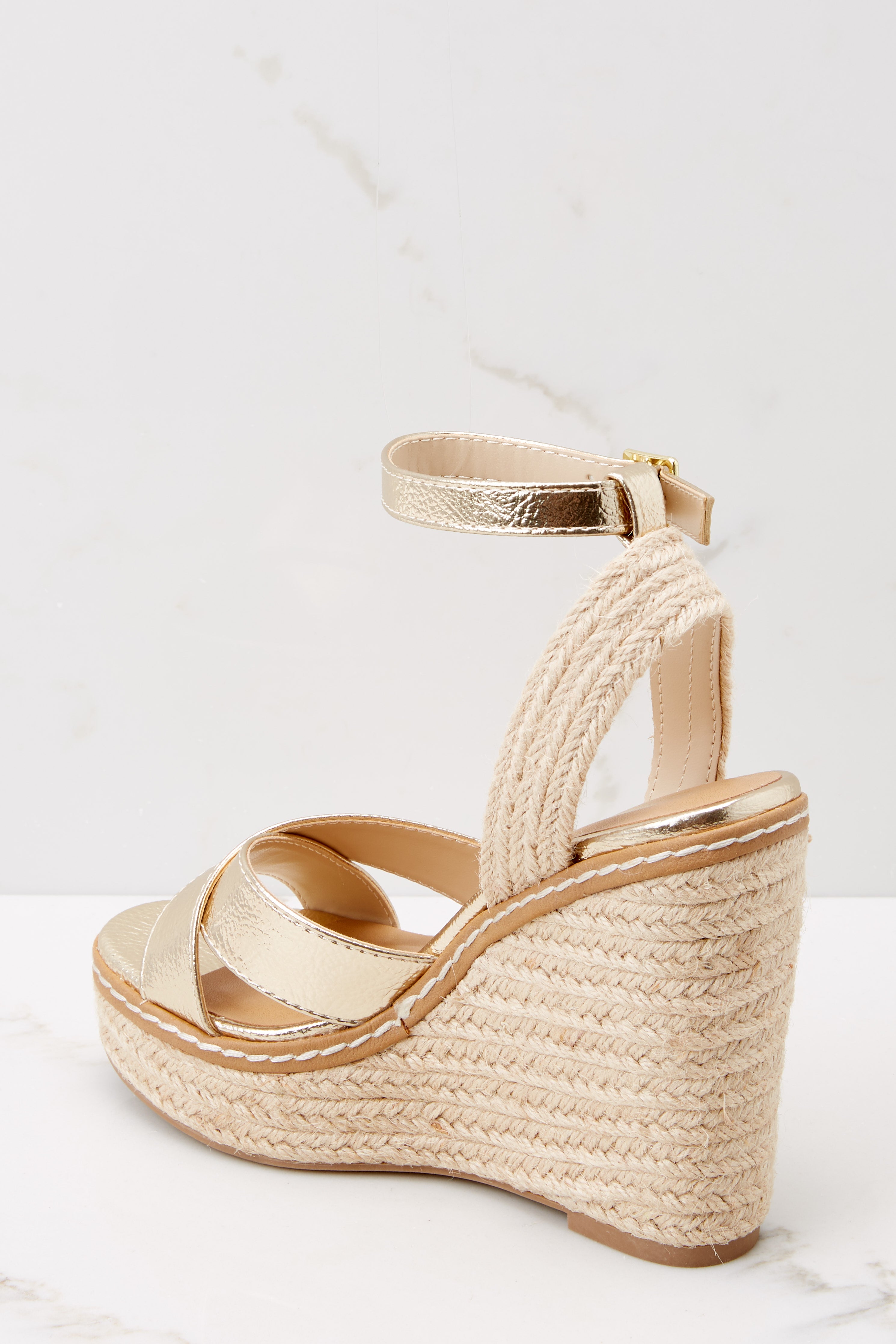 Back view of a 5 inch espadrille wedges with a metallic gold sole and straps, and an adjustable strap at the ankle.