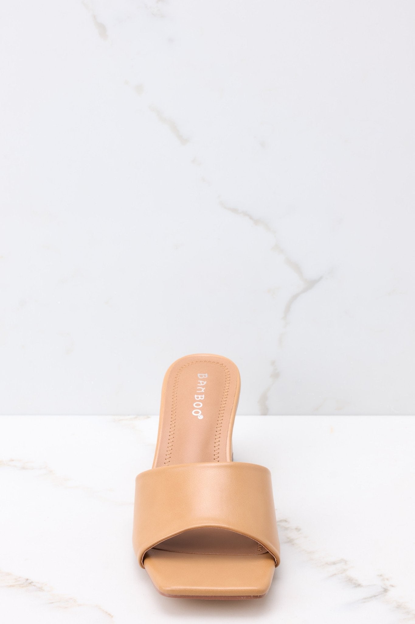 Front view of these heels that feature a square toe, a thick strap across the top of the foot, a square heel, a faux-leather finish , and a slip-on design.