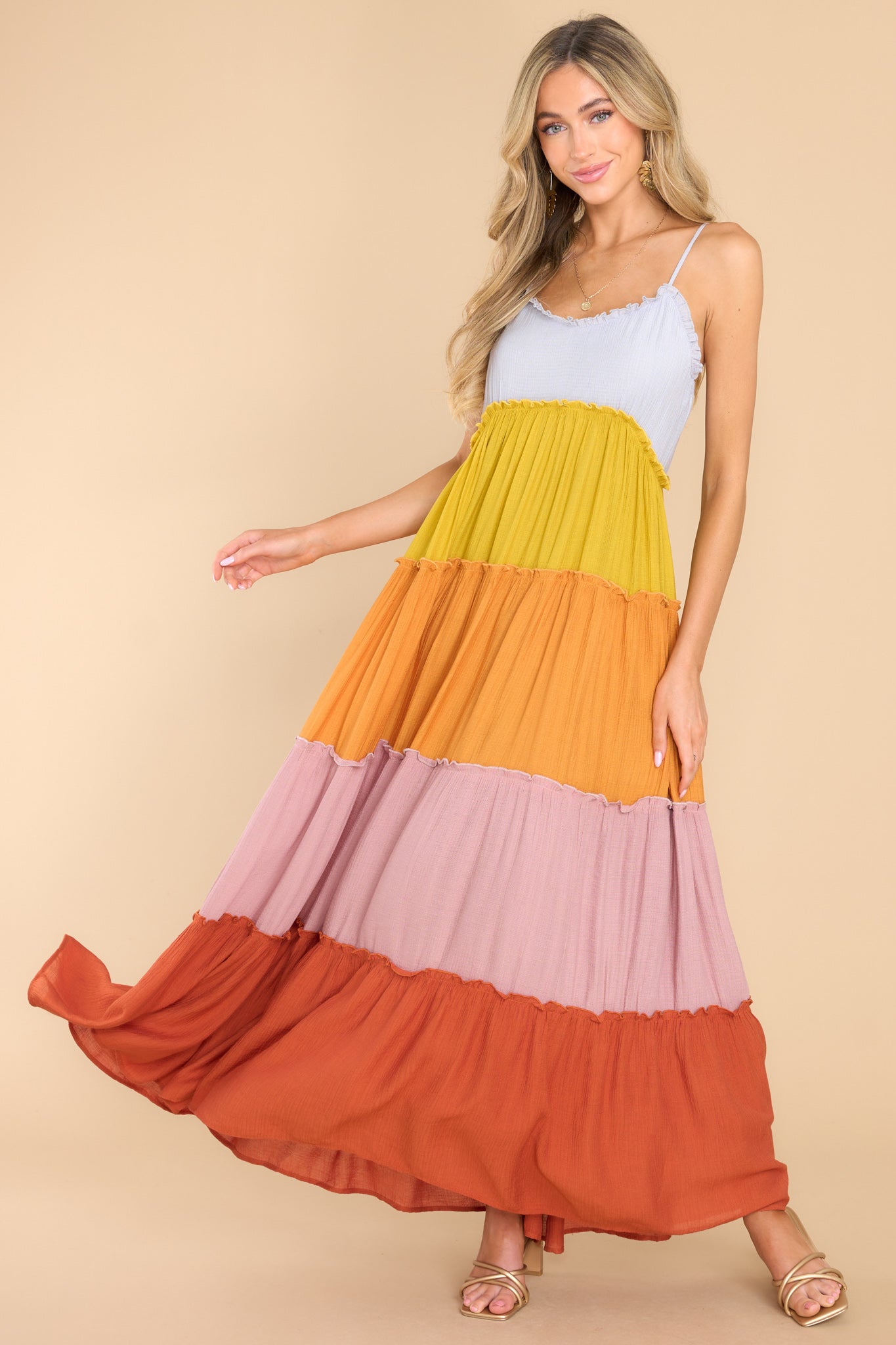 This multi-colored dress features a sweetheart neckline with ruffle detailing, thin adjustable shoulder straps, functional buttons for closure in the back of the bust, and a multicolored, tiered skirt with ruffle detailing.