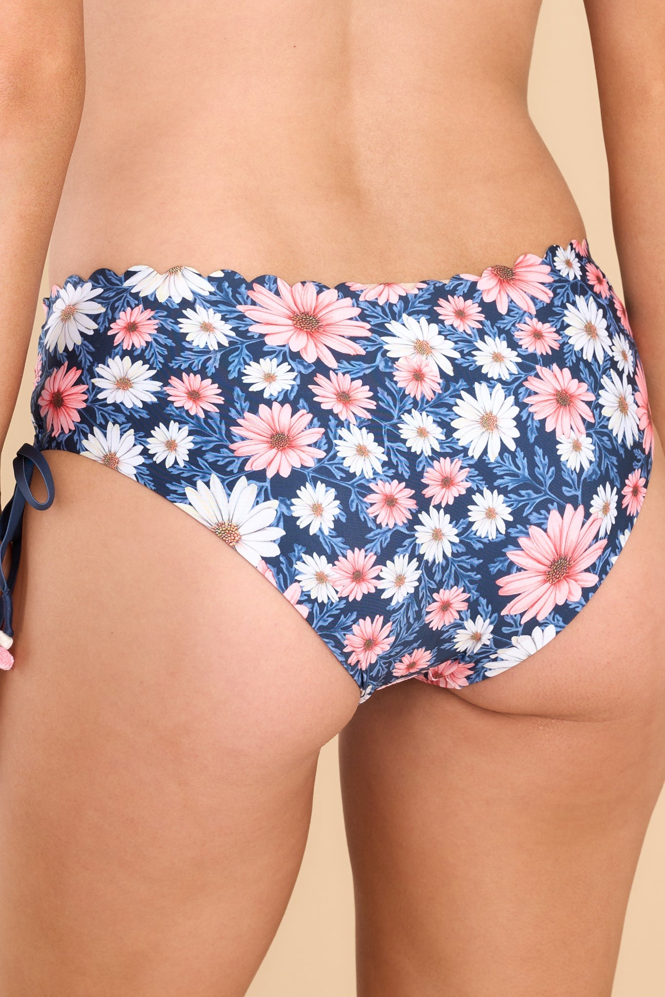 Back view of these bottoms that feature a mid-rise design, scalloped edge detailing, drawstring ties at the sides, and full coverage in the back.