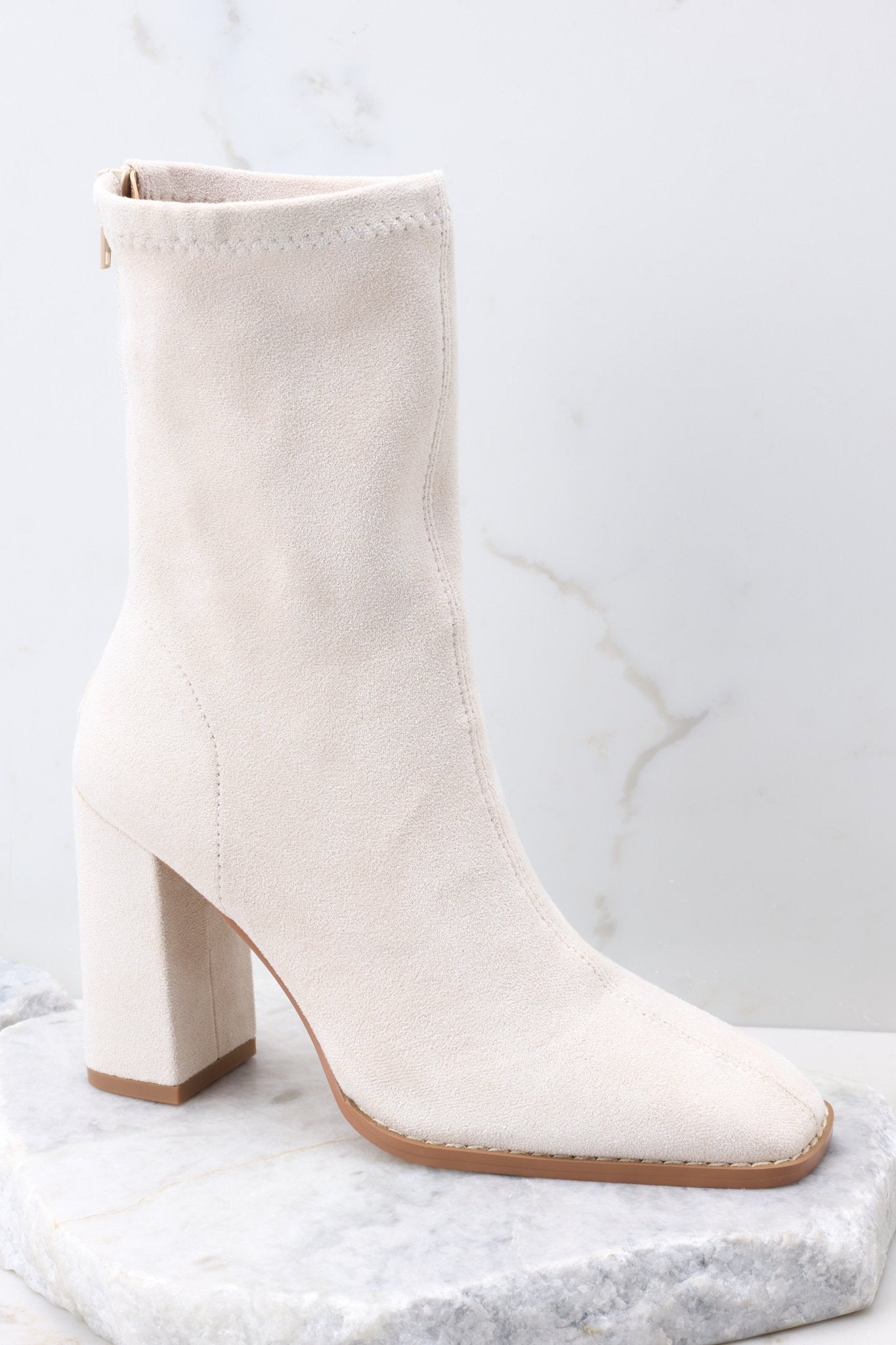 Outside view of ivory booties featuring a square toe, and a block heel.