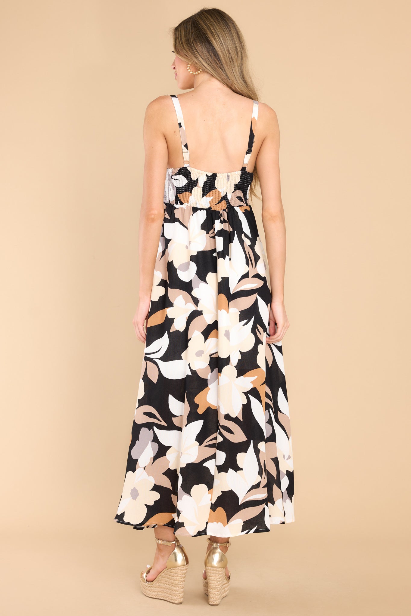 Back view of this dress that features a square neckline, adjustable straps, a smocked section at the back of the bust, and a flowy skirt.