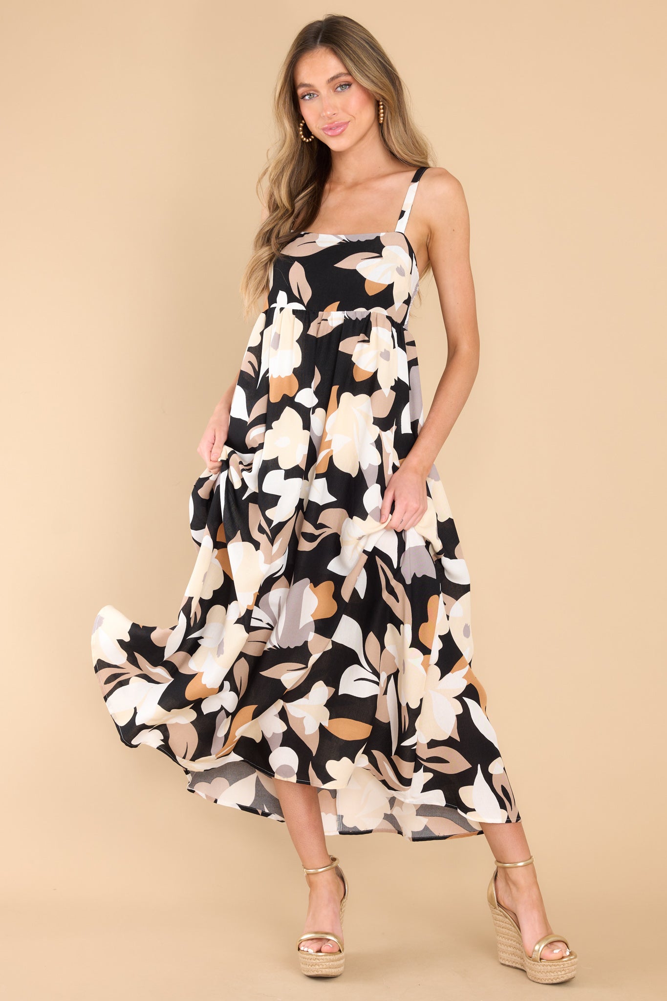 Full body view of this dress that features a square neckline, adjustable straps, a smocked section at the back of the bust, and a flowy skirt.