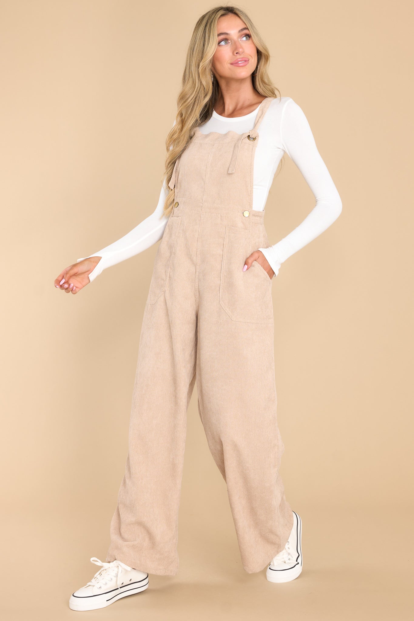 Full body view of these overalls that feature adjustable self-tie straps, four functional side pockets and two back pockets, buttons below the bust to allow for a folded look, and a corduroy texture throughout.