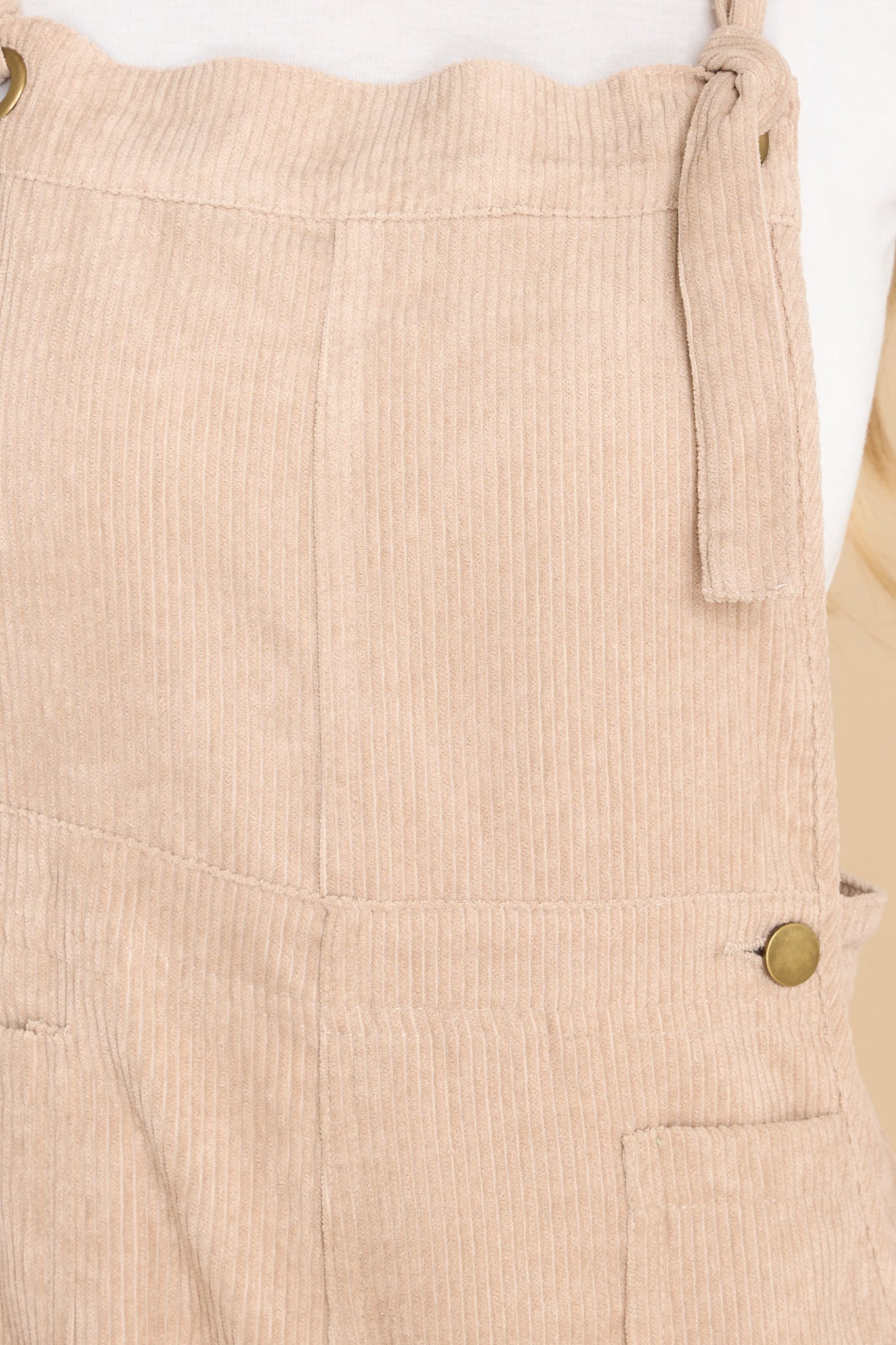 Close up view of these overalls that feature adjustable self-tie straps, four functional side pockets and two back pockets, buttons below the bust to allow for a folded look, and a corduroy texture throughout.