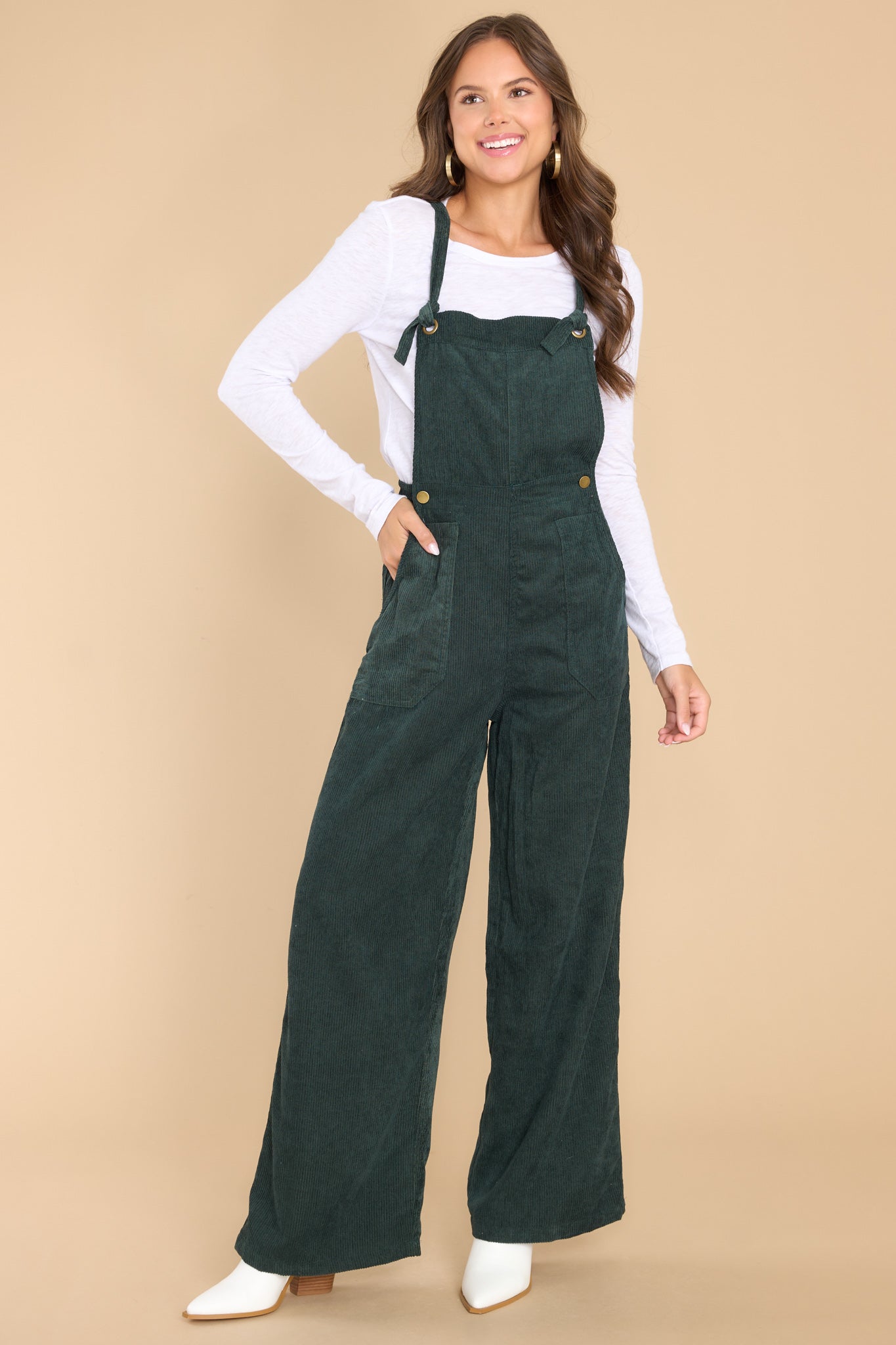 Full body view of these overalls that feature adjustable self-tie straps, four functional side pockets and two back pockets, buttons below the bust to allow for a folded look, and a corduroy texture throughout.