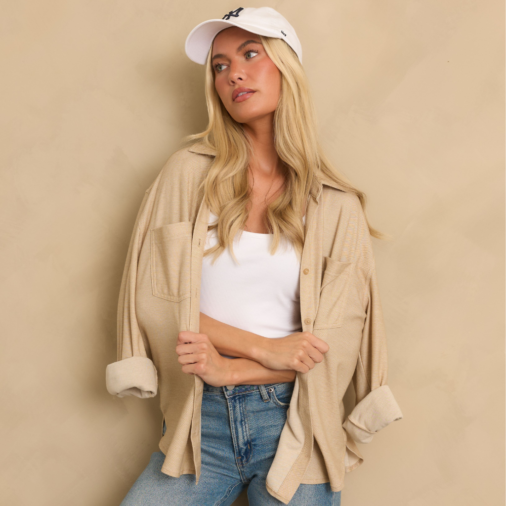 Women's Refresh for Fall outfit featuring an oversized beige button-up shirt, white cropped tank, light-wash jeans, and a baseball cap.