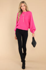 This hot pink sweater features a scoop neckline, long dolman sleeves, large ribbed knitting, and a cropped style.