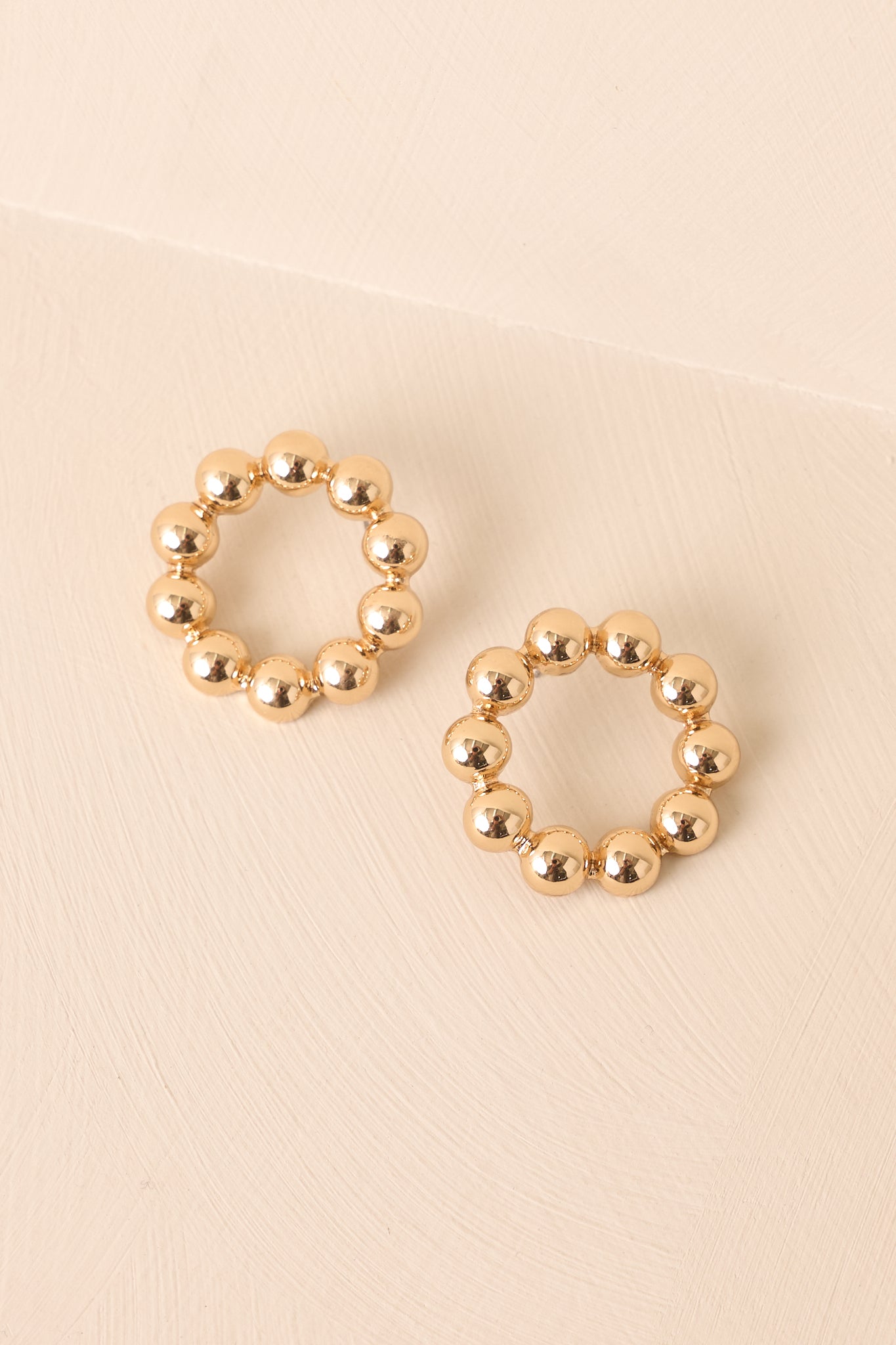 A cropped view of the hollow circle earrings with textured bead details along the loop.