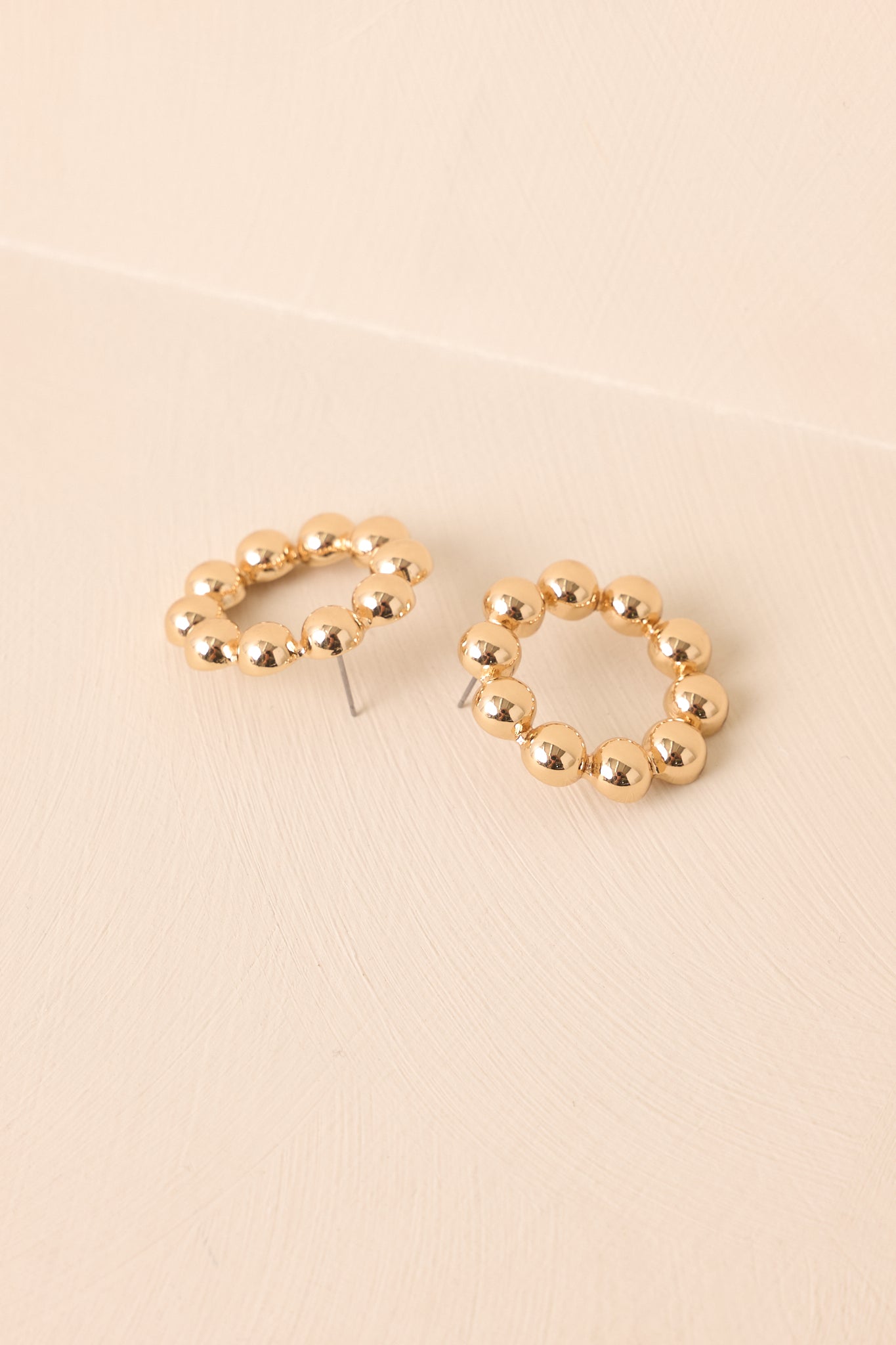 A close-up cropped shot highlighting the circular shape and raised bead accents of the earrings.