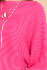 Close up view of this sweater that features a scoop neckline, long dolman sleeves, large ribbed knitting, and a cropped style.