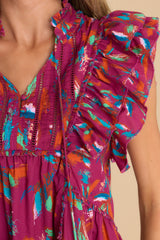 Close up view of this top that features a v-neckline with a self-tie closure and functional buttons, ruffled sleeves and hem, and a tiered design.