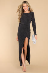 This black dress features a crew neckline, long sleeves, an open back, a front slit, and shimmer detailing.