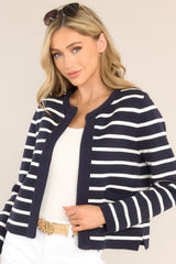 Angled front view of this cardigan that features a round ribbed neckline, long sleeves with ribbed cuffs, ribbed hemline, slits at the sides, and a modern horizontal striped pattern.