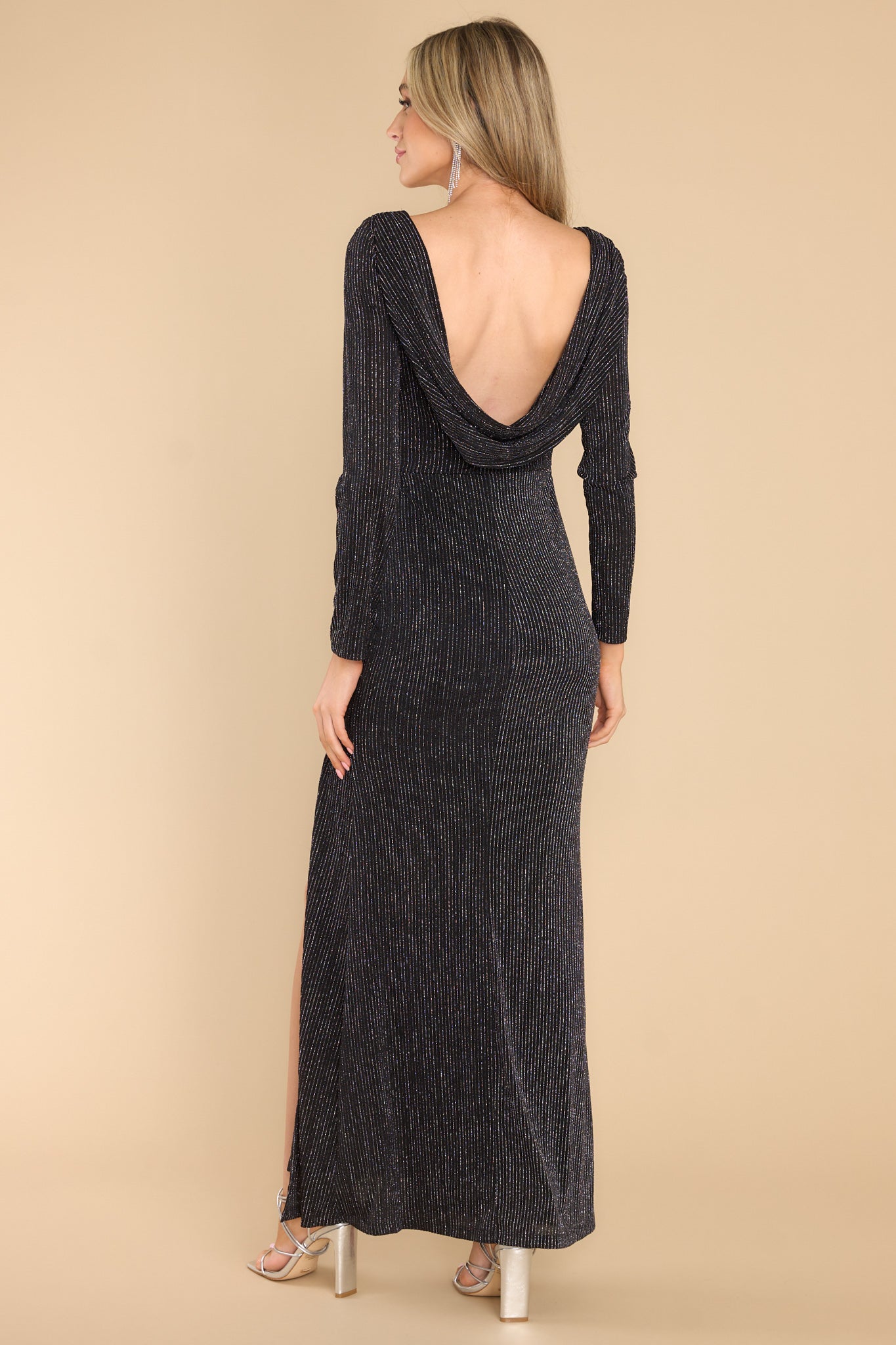 Back view of this dress that features a crew neckline, long sleeves, an open back, a front slit, and shimmer detailing.