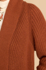 Close up view of  this cardigan that features a folded neckline that extends down the front and a knit texture throughout.